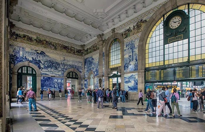 Turister beundrar det vackra azulejo-kaklet inne på tågstationen São Bento i Porto © suitcase_and_wanderlust