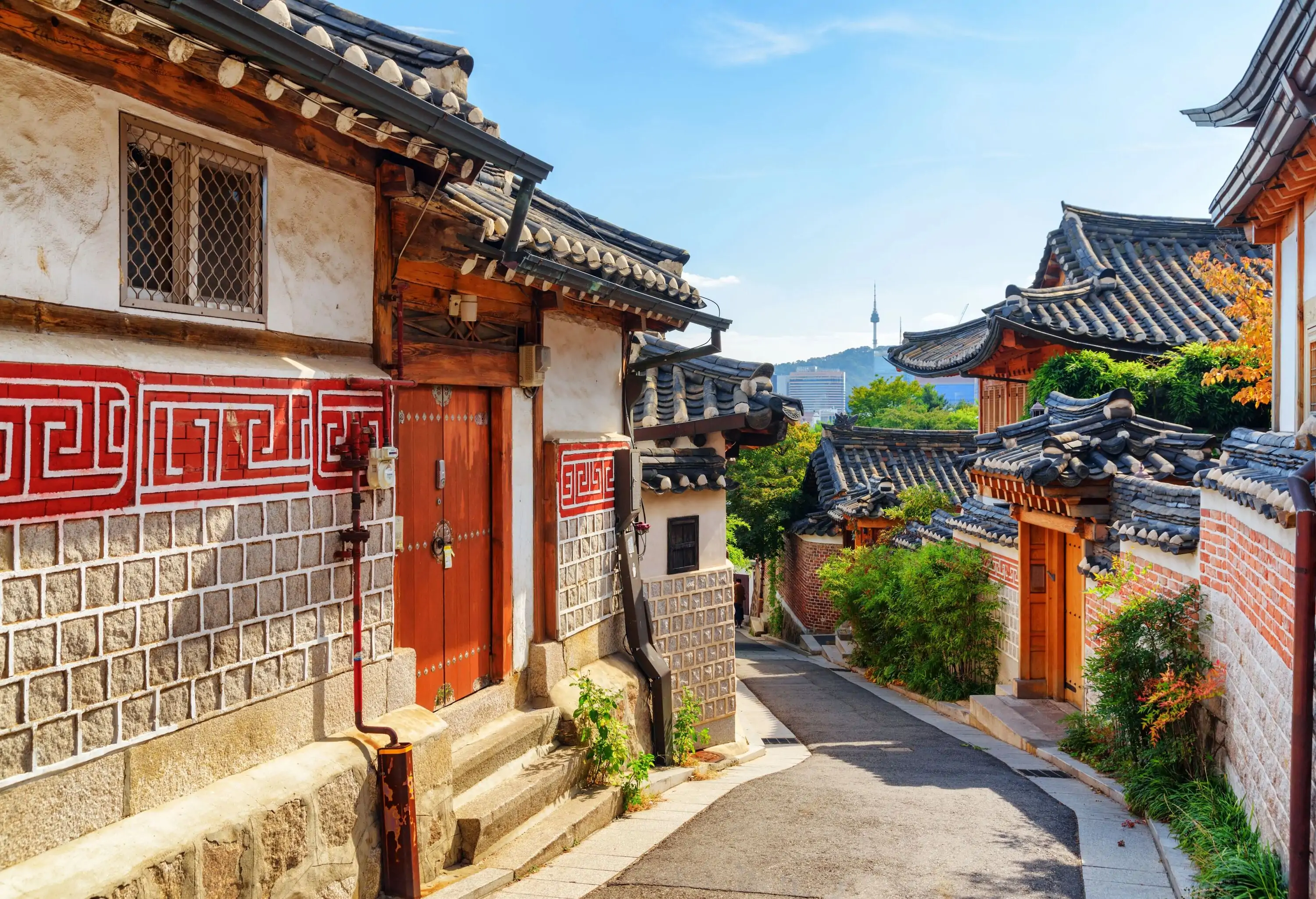 A winding alley in a historic village surrounded by traditional Korean dwellings.