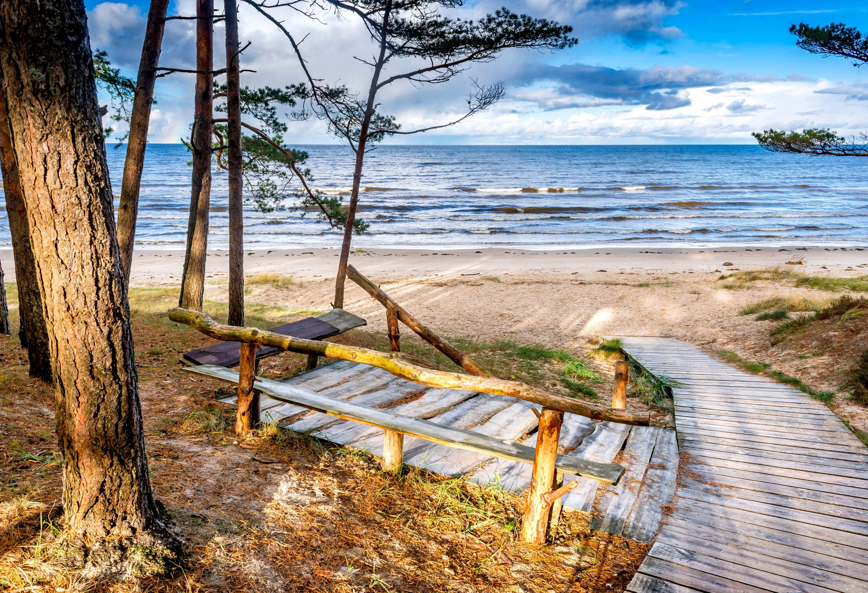 A wooden pathway slope down the beach against the scenic sky.