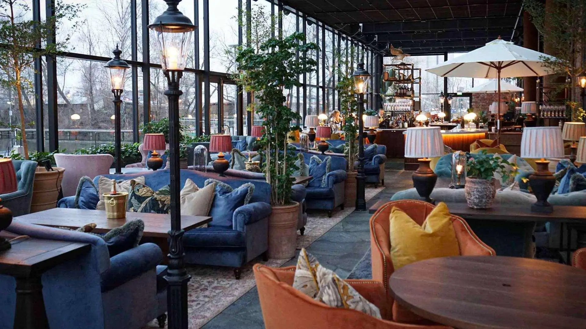 ecadent hotel lobby with sets of plush blue velvet sofas by large industrial style windows