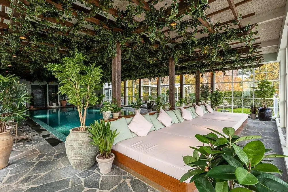 Spa pool in modern hotel surrounded by glass windows and greenery