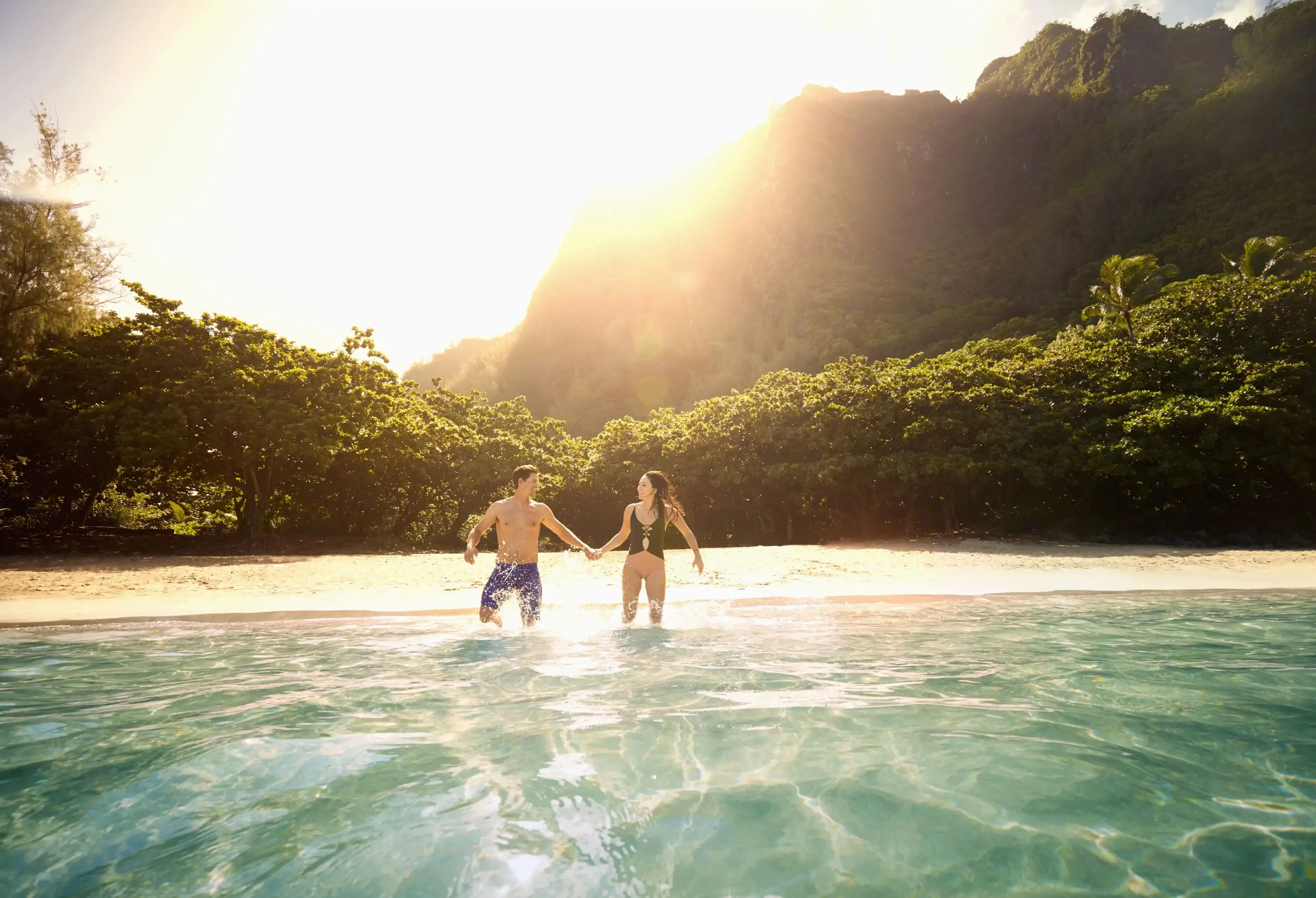 Couple jumping into water at a tropical beach