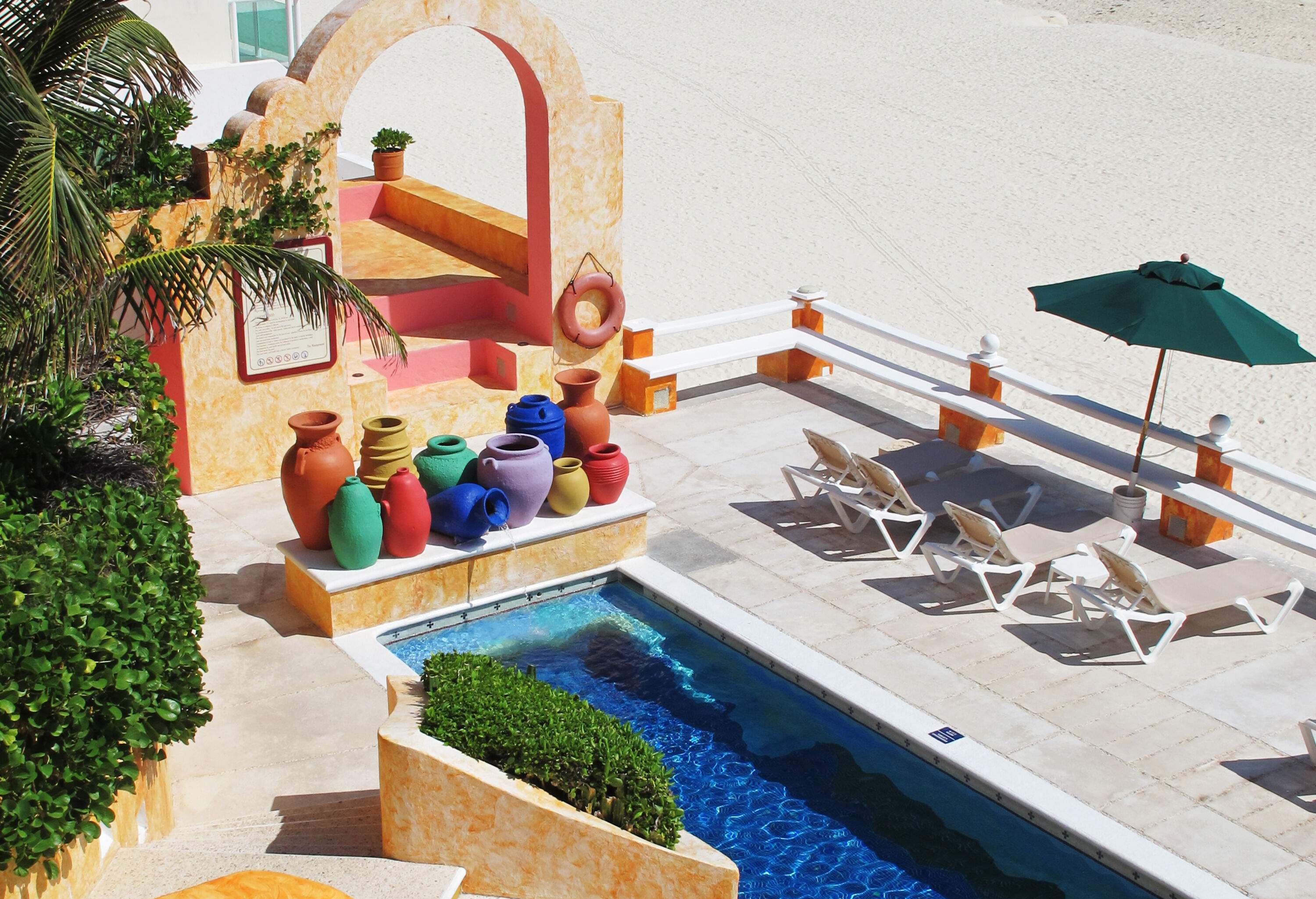 A beachfront balcony with a pool and sunbeds overlooking a vast ocean.