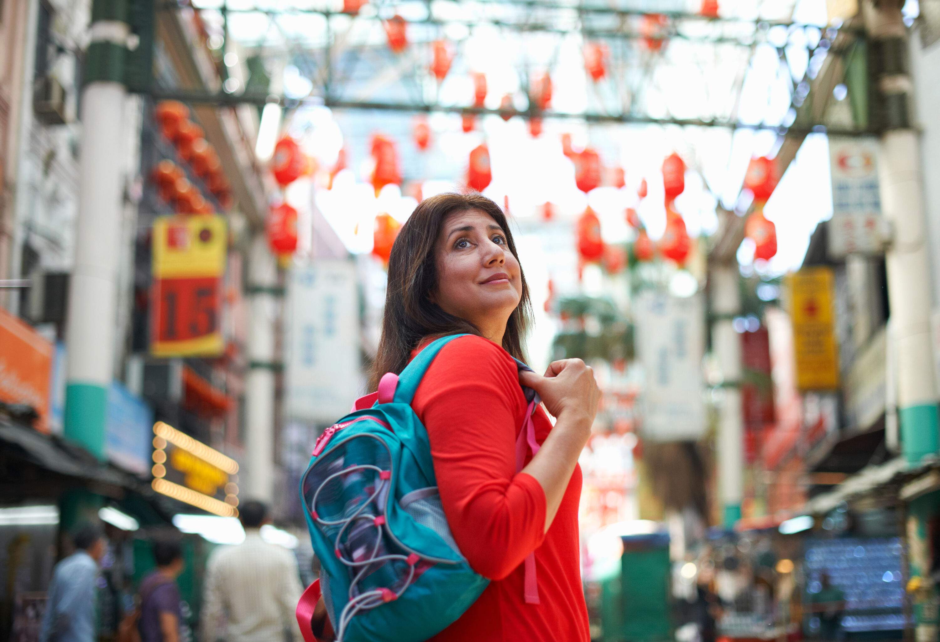 A woman tourist carrying a backpack explores the street between the colourful buildings.