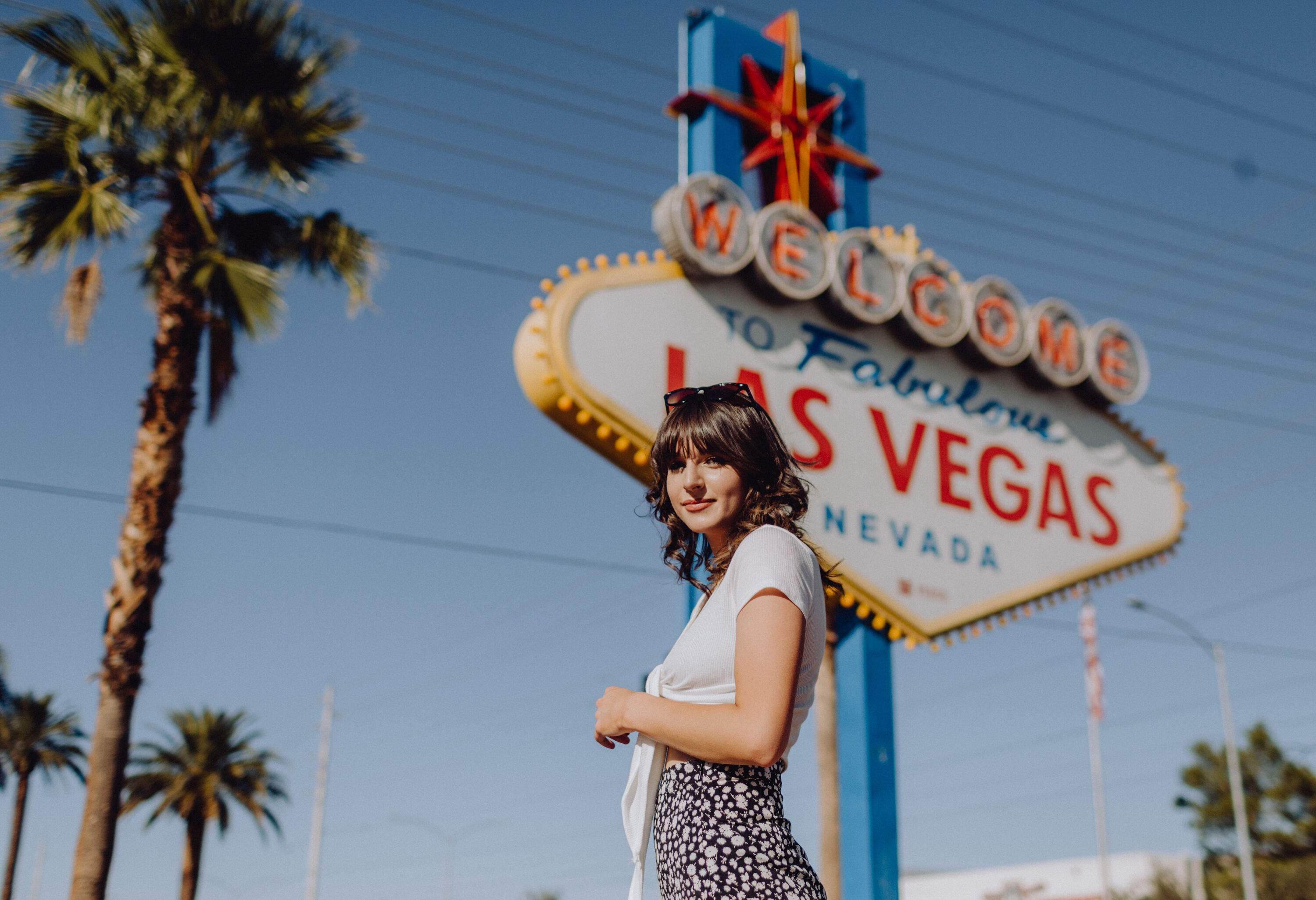 A beautiful young woman standing in front of the Welcome to Fabulous Las Vegas sign.