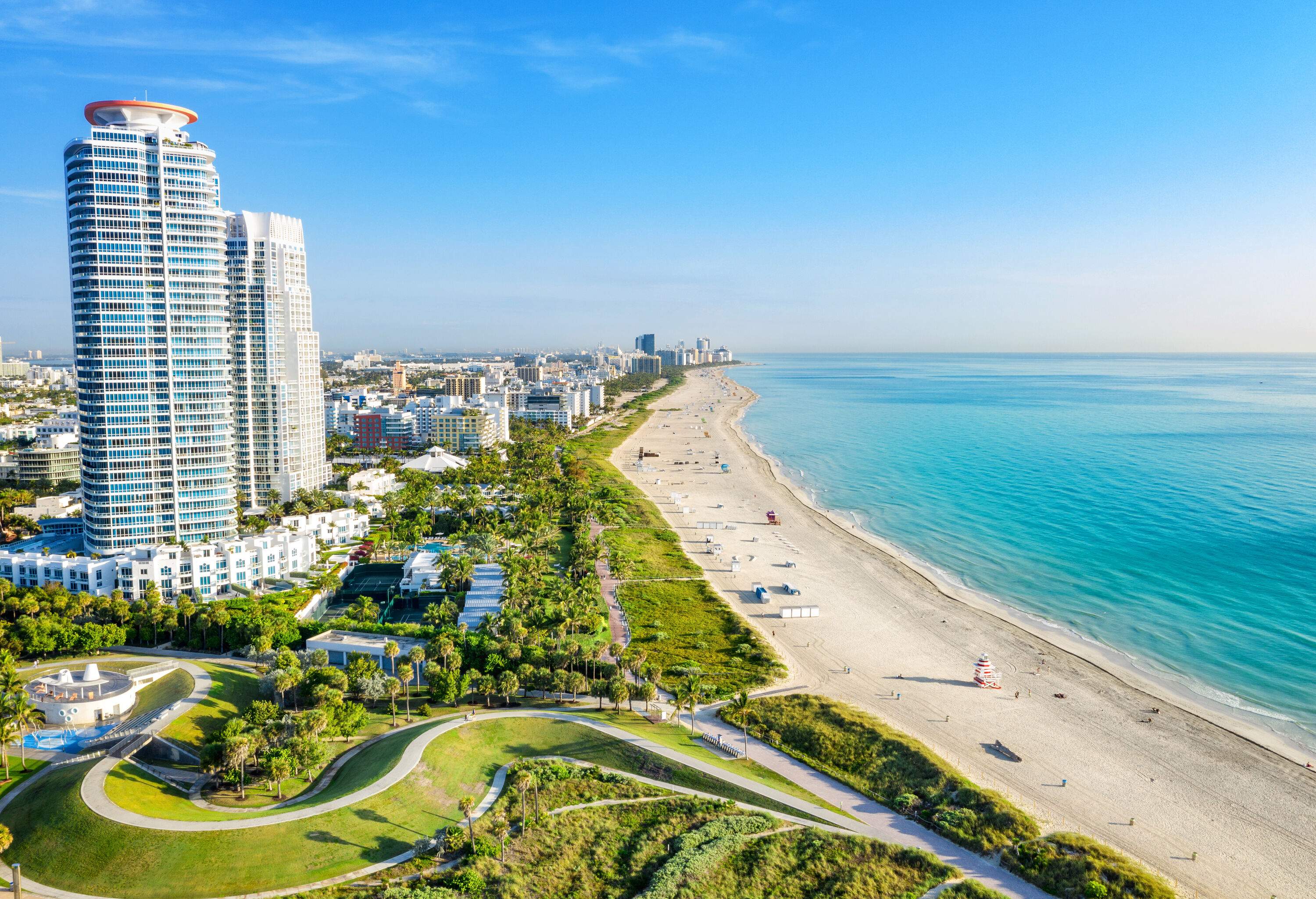 An extensive stretch of sandy beach bordered by towering hotels with ocean views.