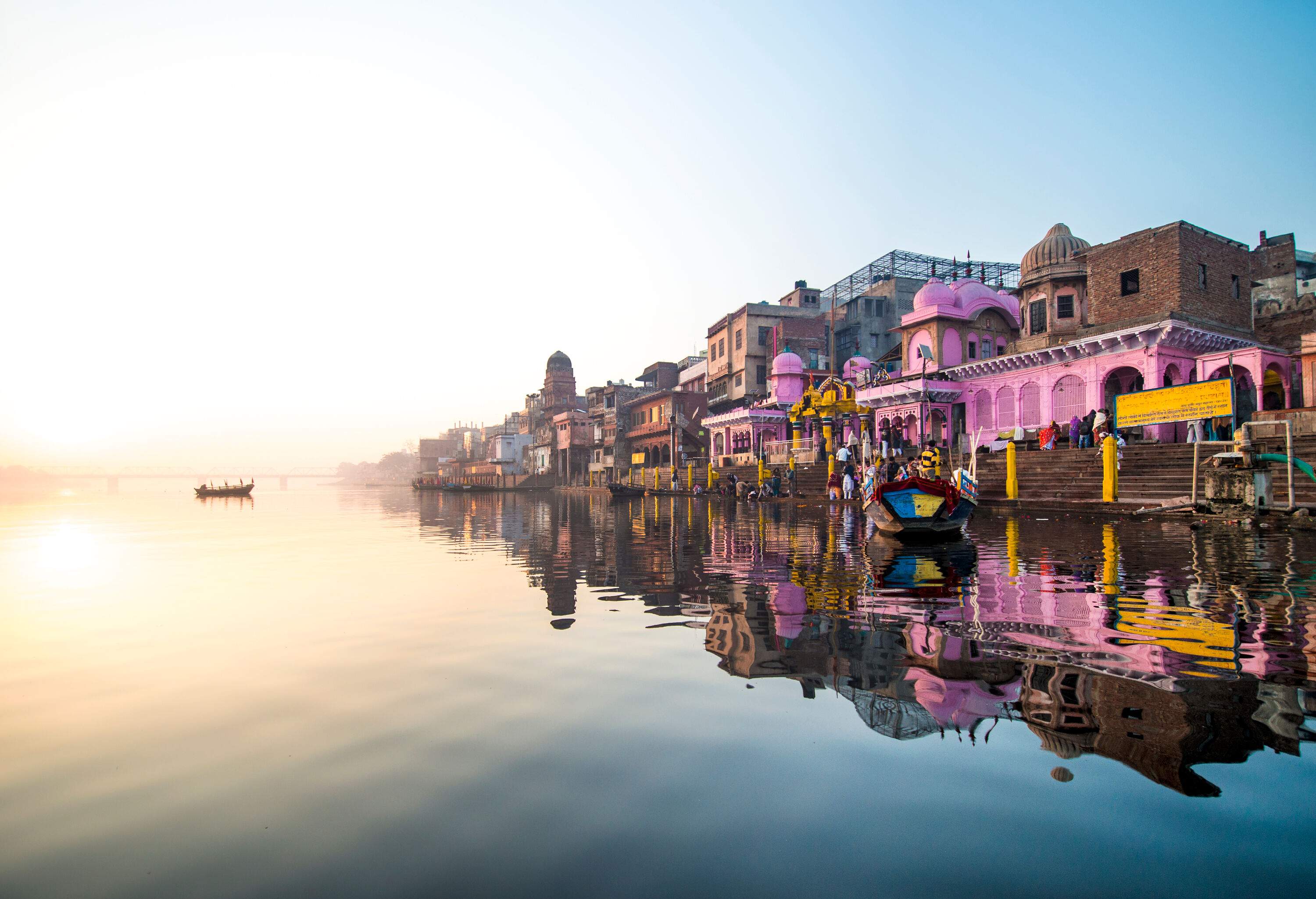 A calm river reflects the image of a city's waterfront structures.