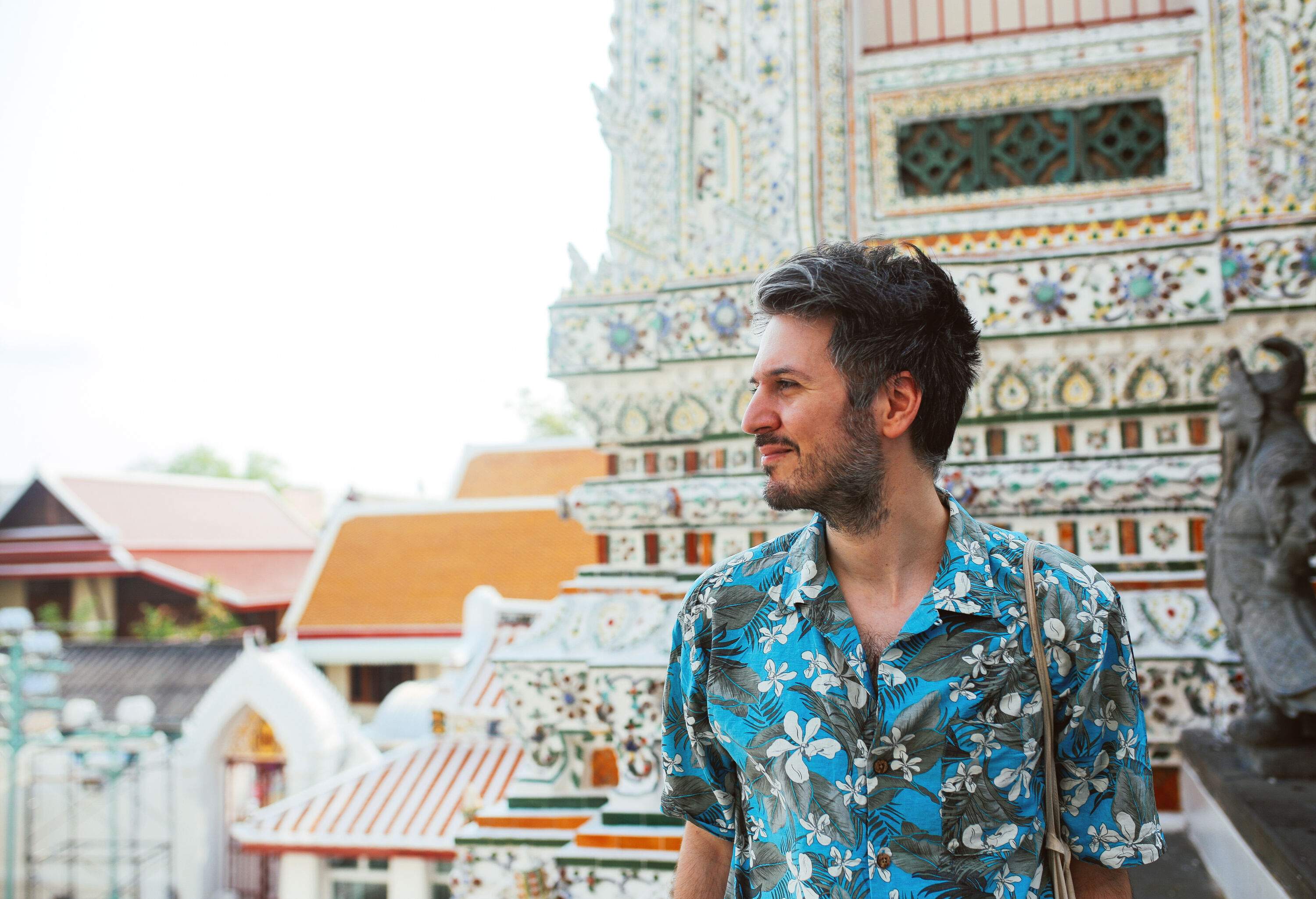 A bearded man against the colourful temple in the background.