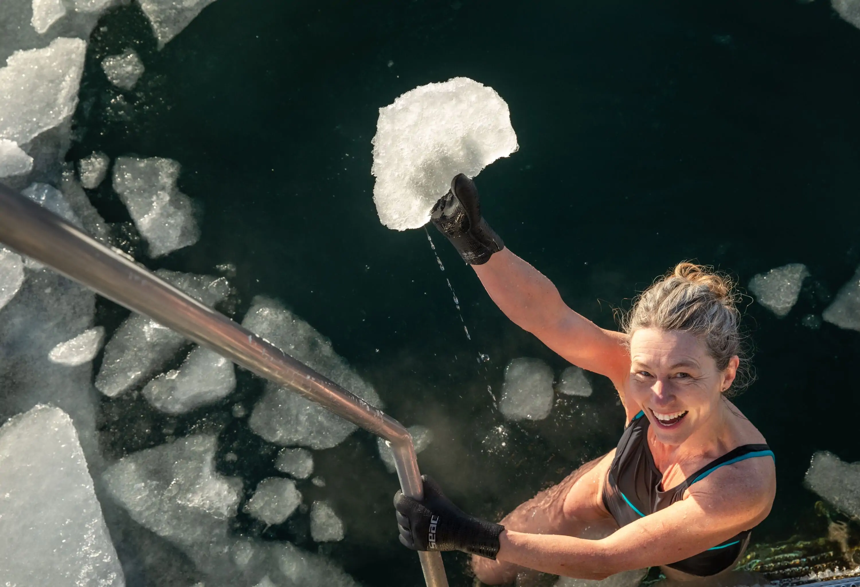 Happy Swimmer Holding Chunk Of Ice From Freezing Water in ice hole