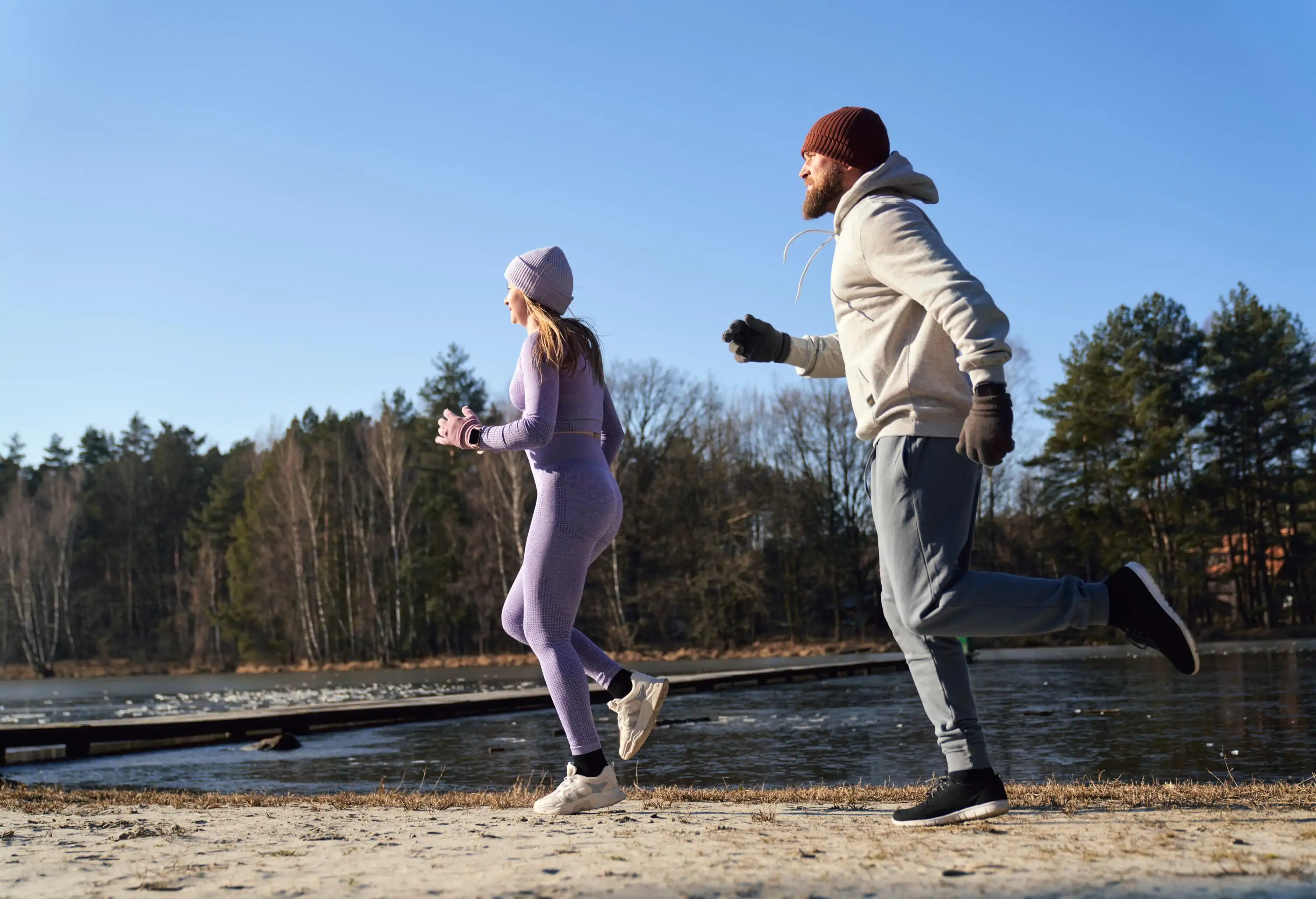 Adult caucasian couple warming up before winter swimming on a sunny winter day