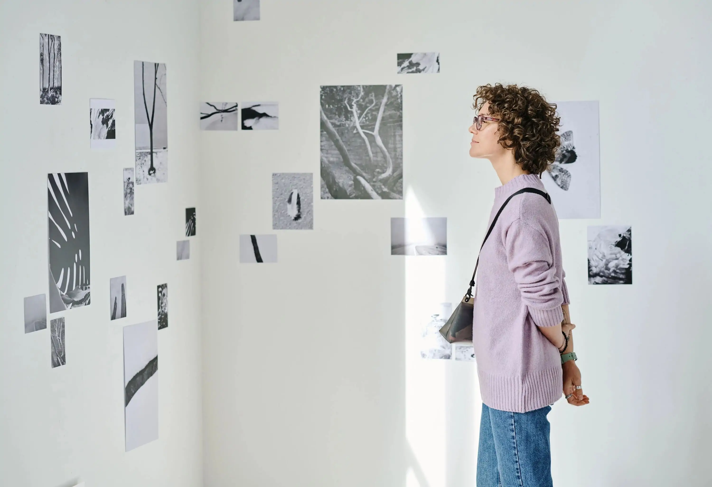 Young woman looking at photos on the wall during exhibition at art gallery