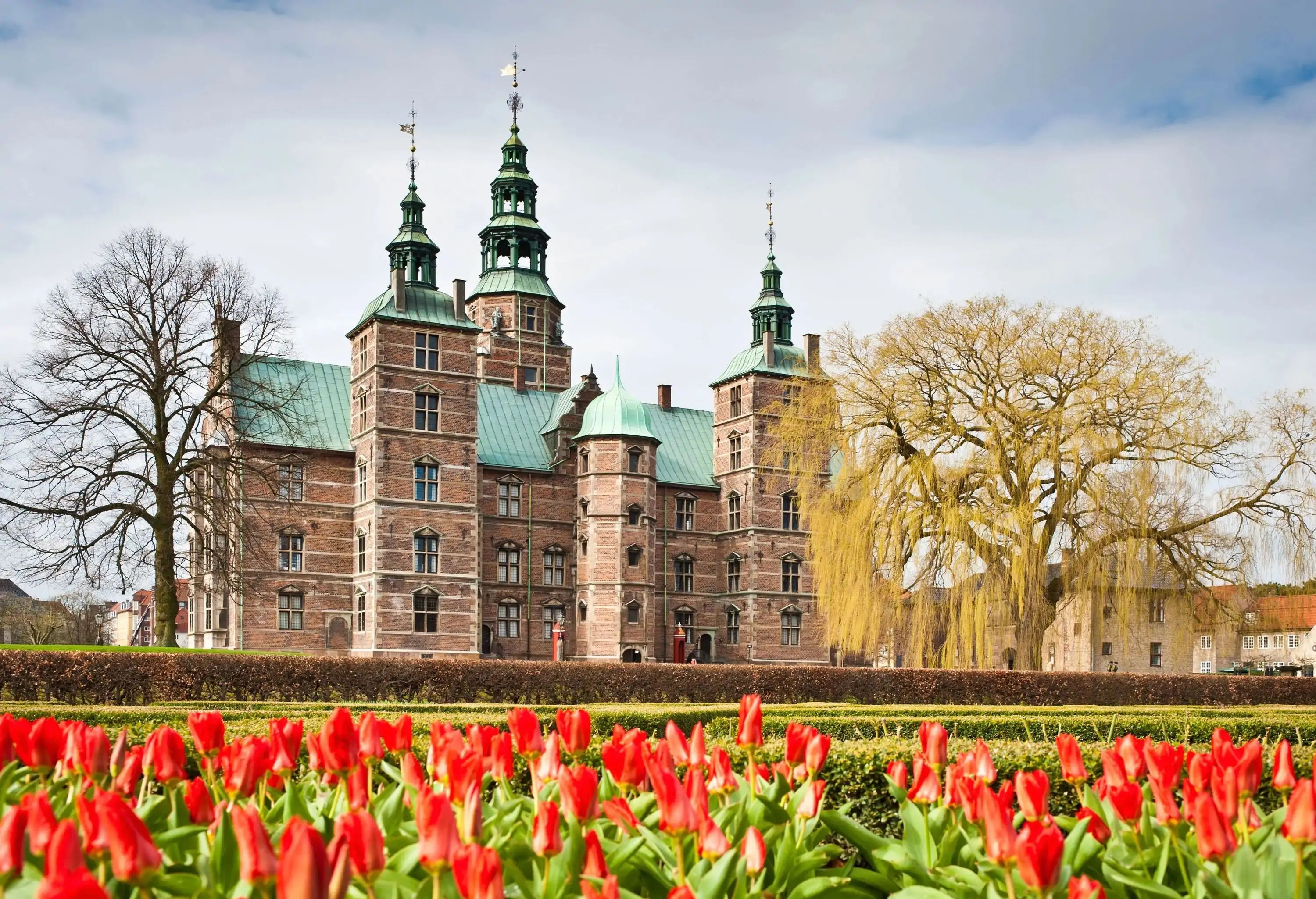 The renaissance spires of Rosenborg Castle overlooking the tranquil green oasis of Kongens Have, The King's Garden, with vibrant red tulips blooming in the spring sunshine. ProPhoto RGB profile for maximum color fidelity and gamut.