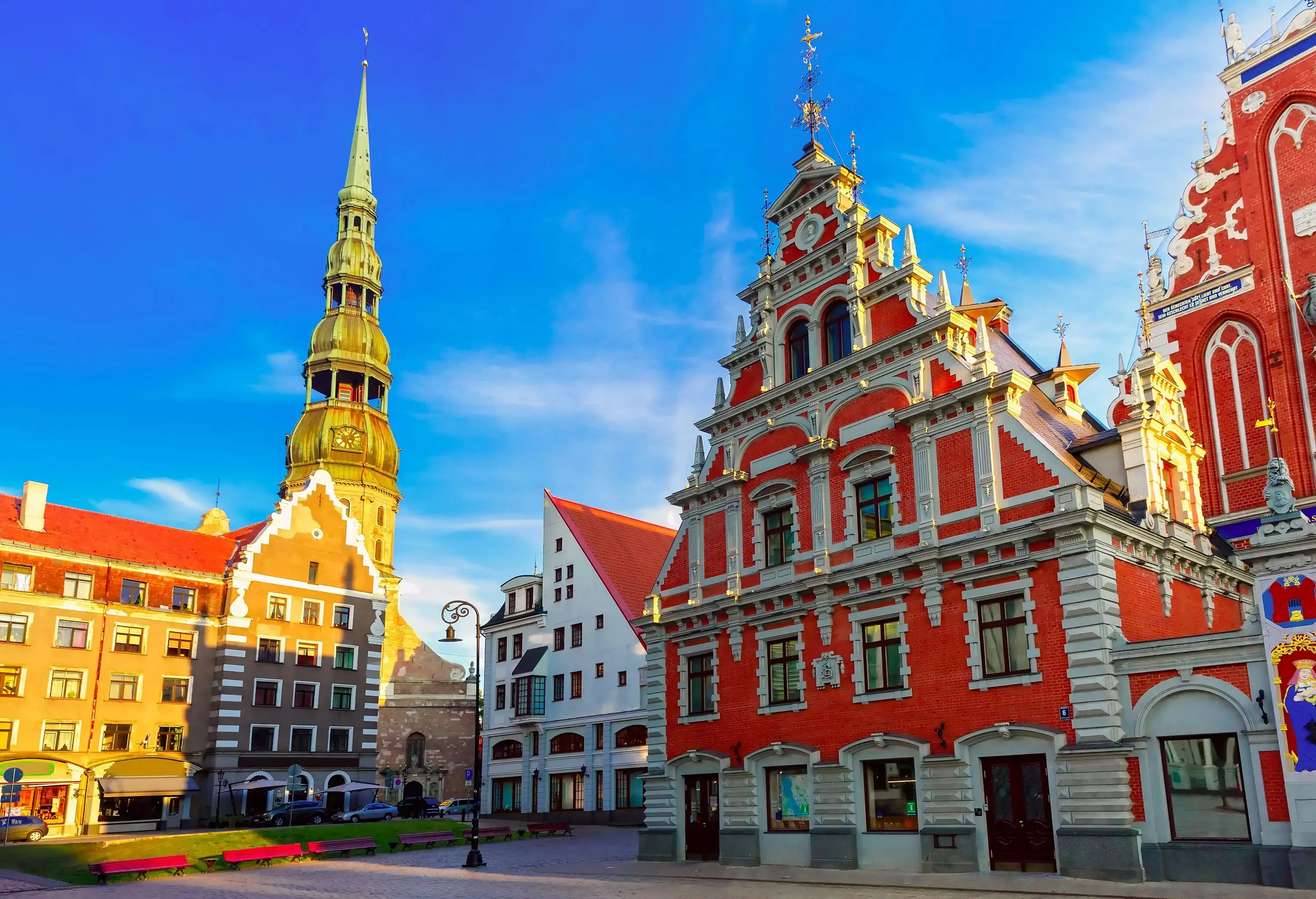 An orange ornate magnificent building line with other structures encloses the city square.