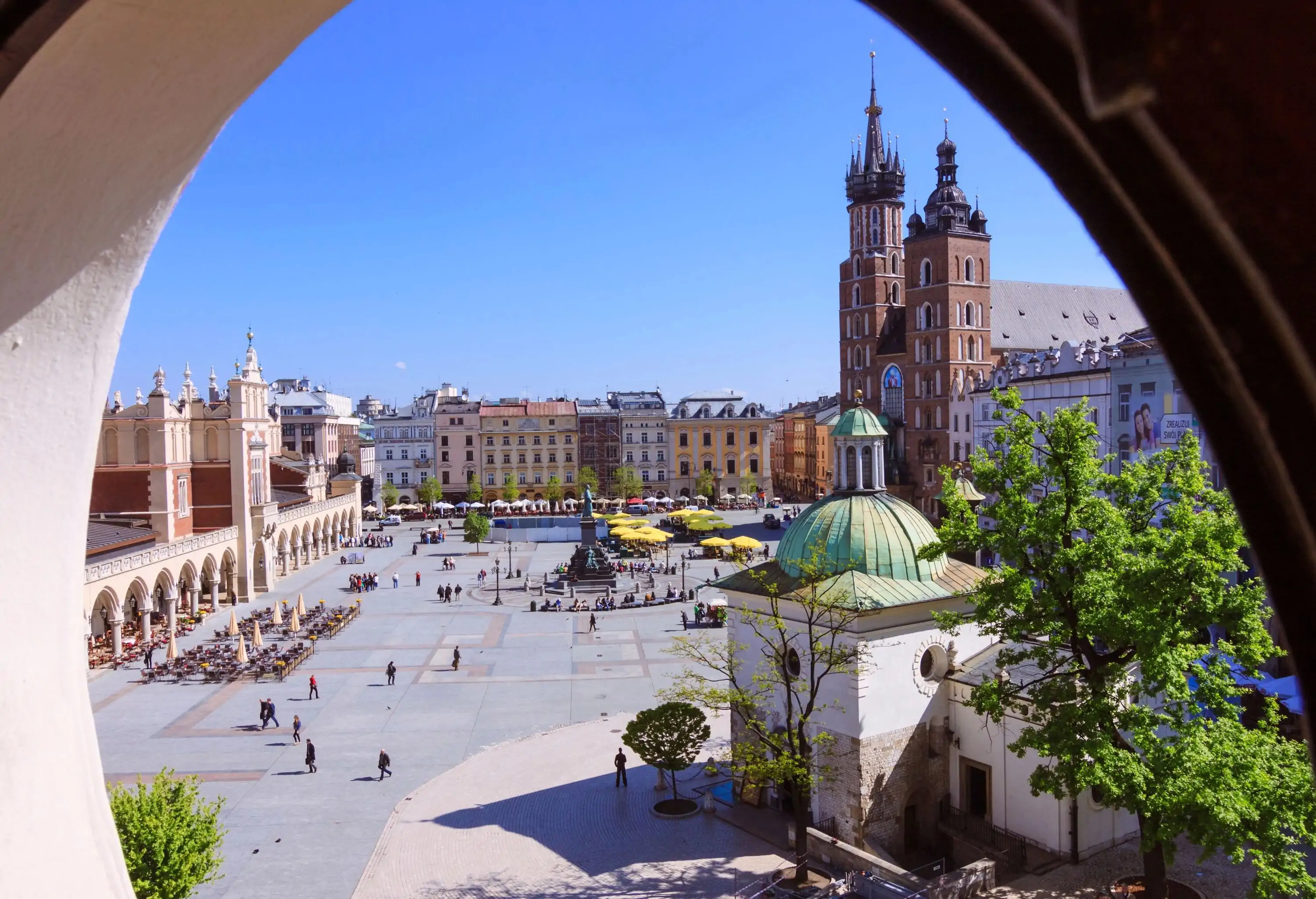 Krakow, Poland : Basilica of Saint Mary , Sukiennice (Cloth Hall) and Church of St. Adalbert at the Main Market Square as seen through a round attic window.