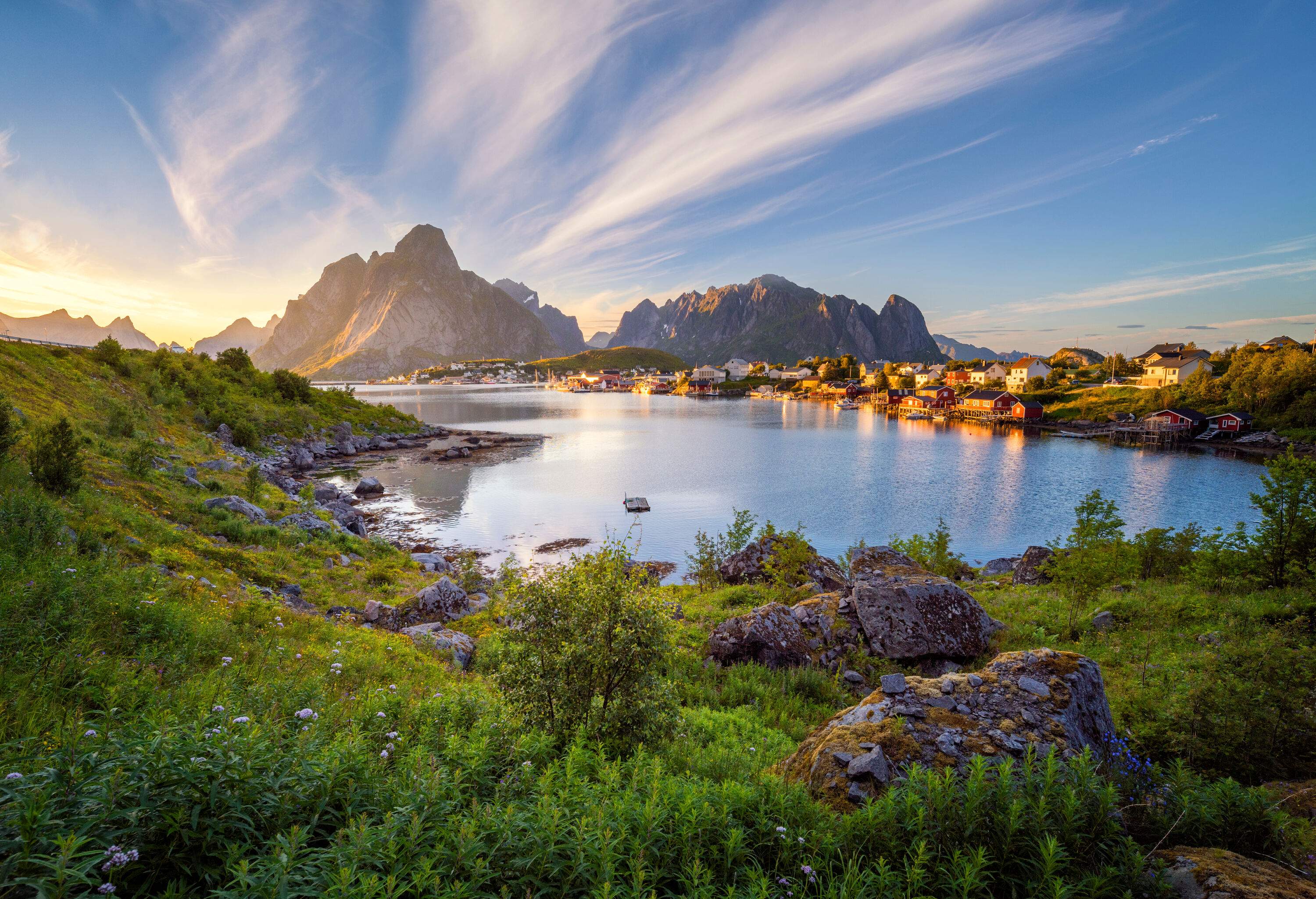 A small waterfront village with craggy mountains in the background.