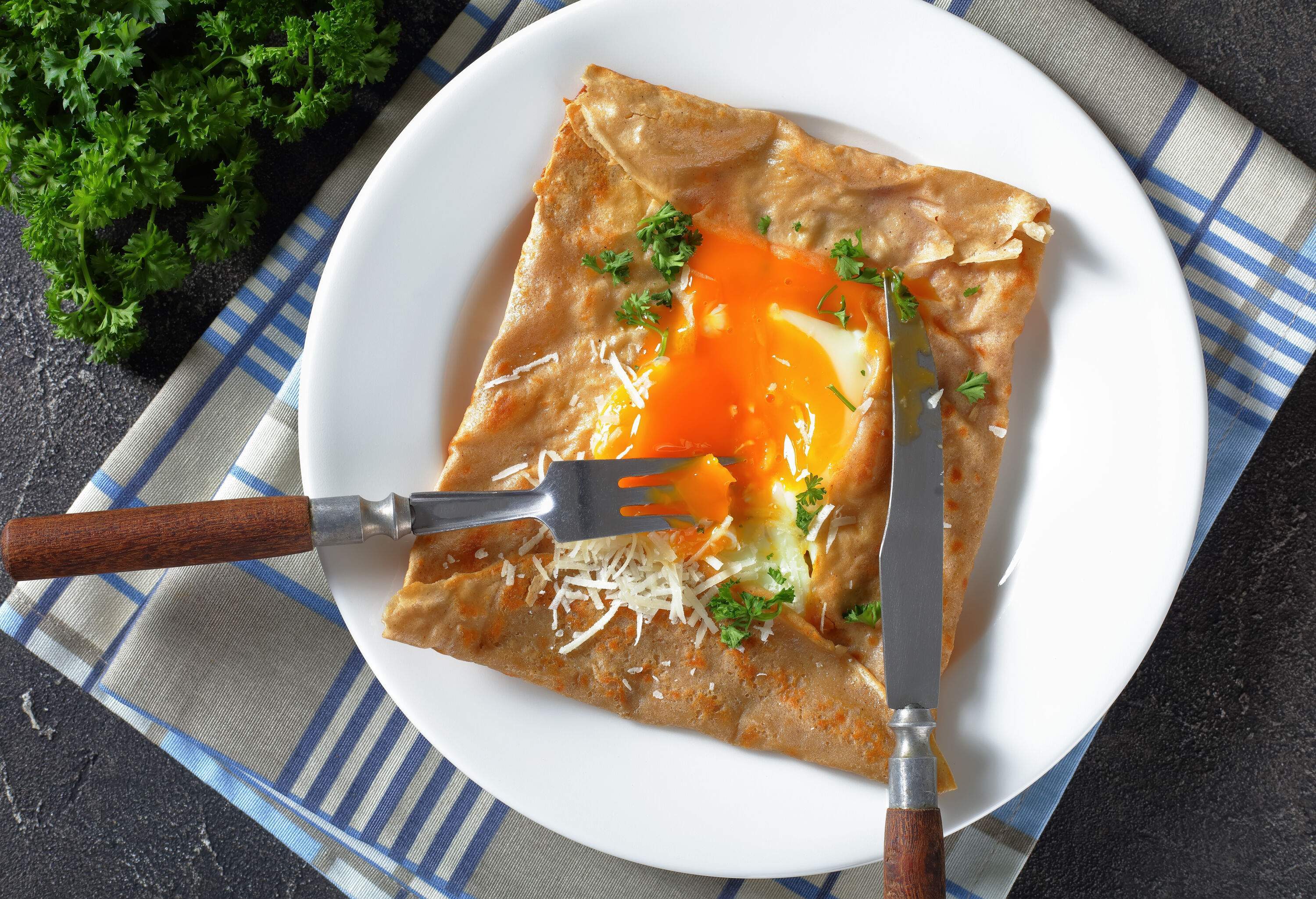 An egg galette garnished with finely chopped parsley and shredded cheese.