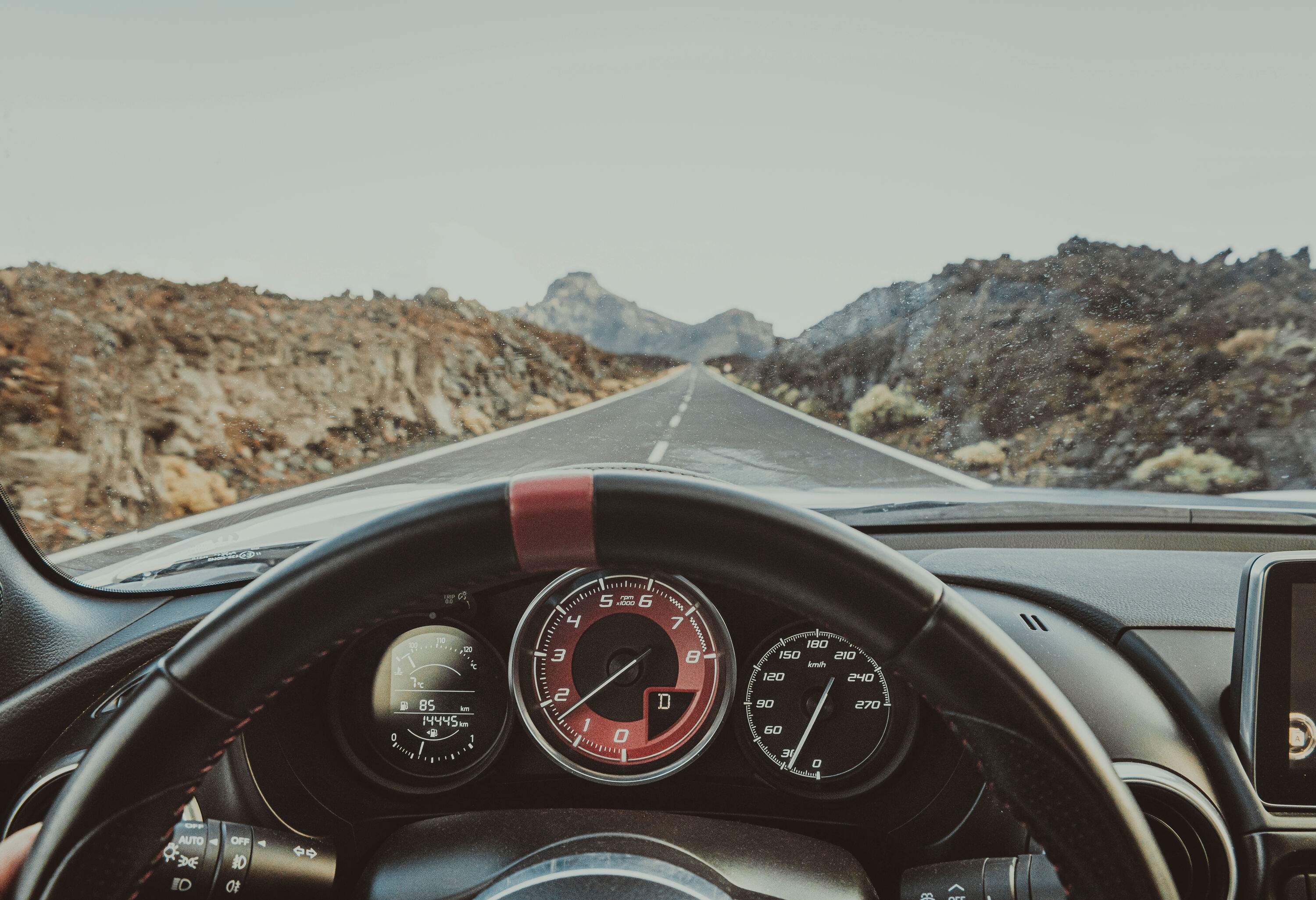 The rocky mountain road is seen from inside the car.