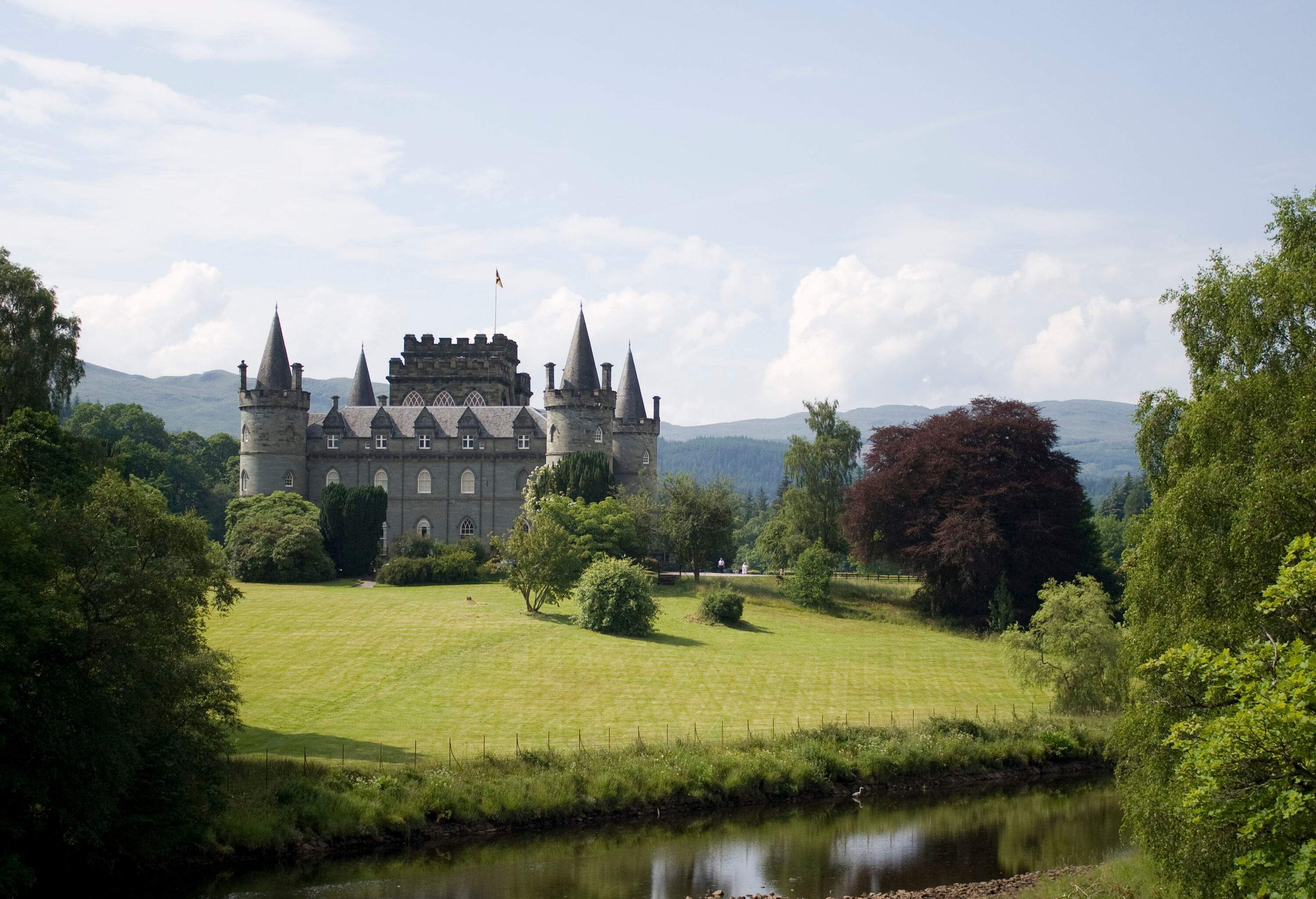 View of a well maintained castle by a river.