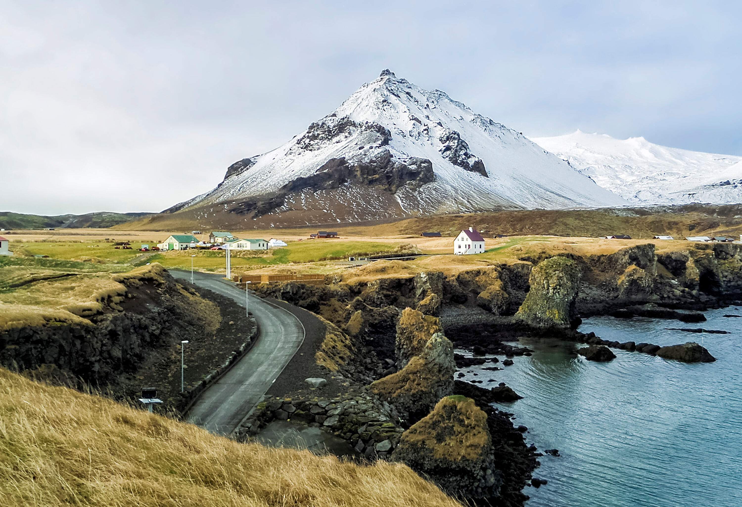 A grassy valley surrounding a snowy mountain dotted with charming cottages.