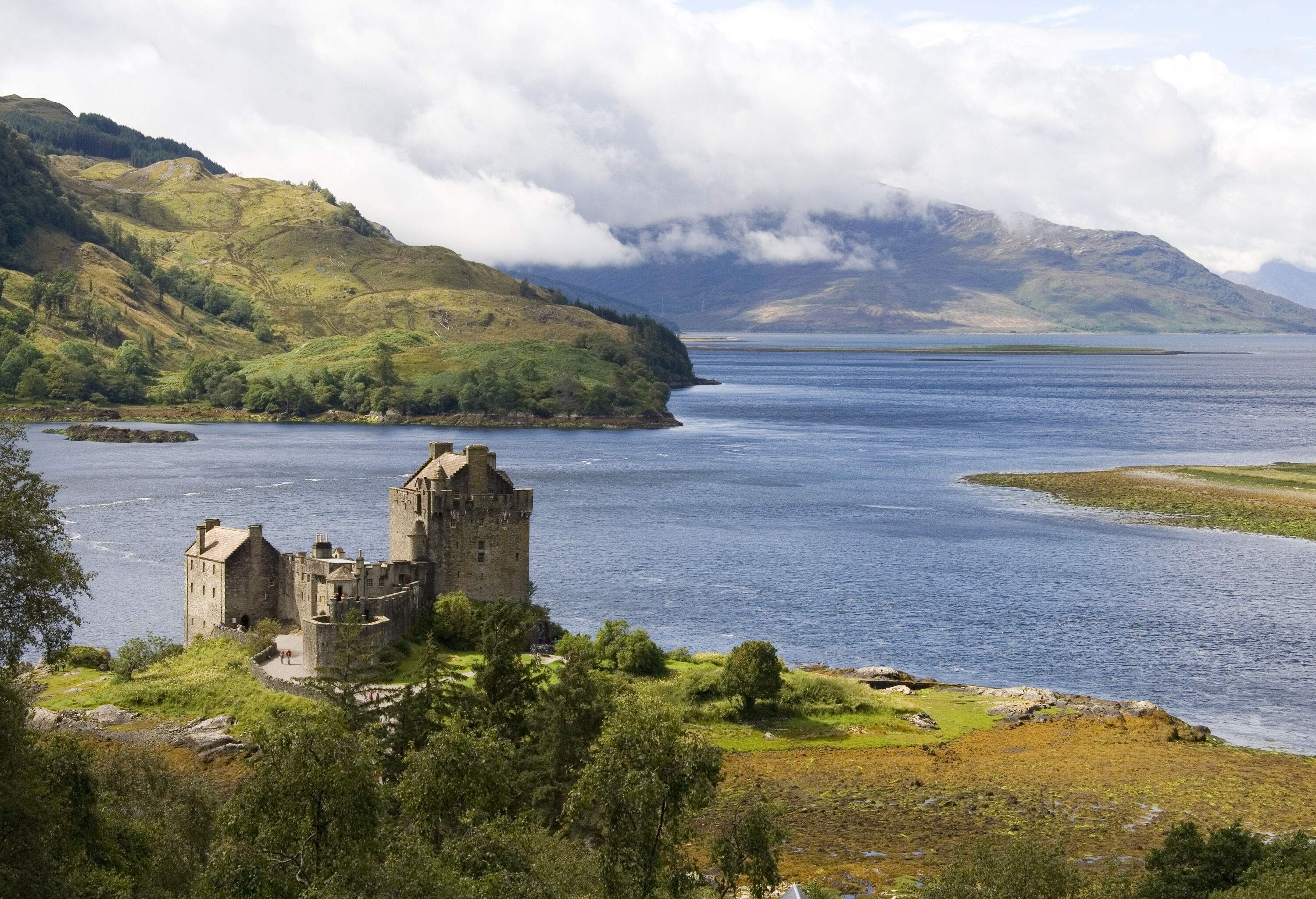 Eilean Donan is a large curtain-walled castle set on a hill with views of a lake and neighbouring mountains.