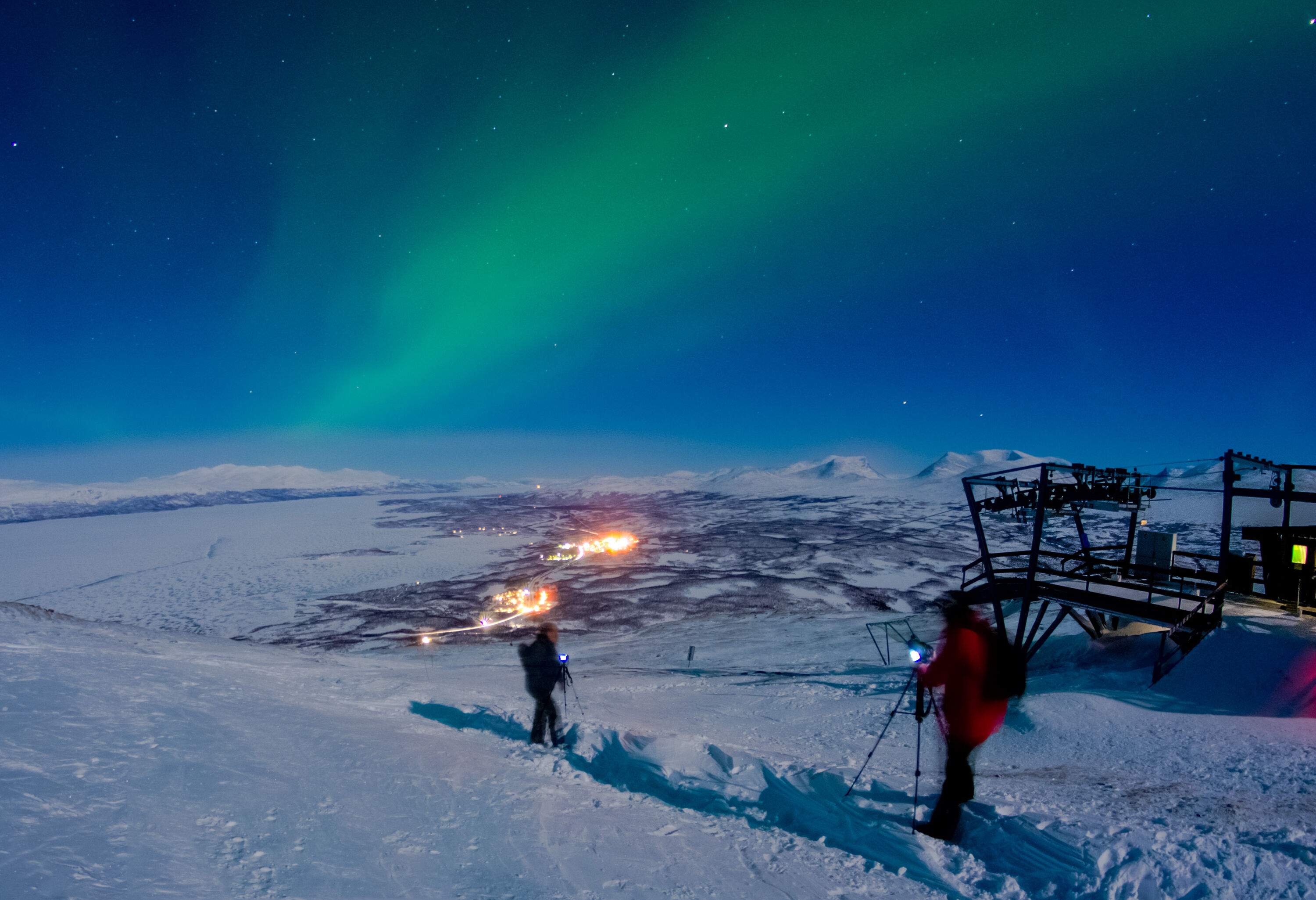 Campers setting up their cameras on tripods to capture the best view of the northern lights as they move across the sky.