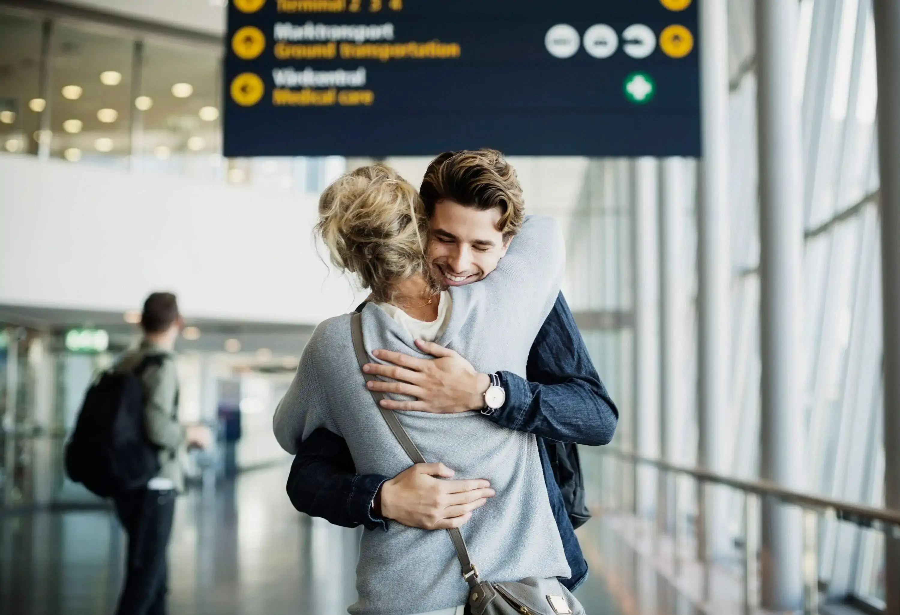 A heartwarming scene of people embracing and smiling with joy in an airport terminal.