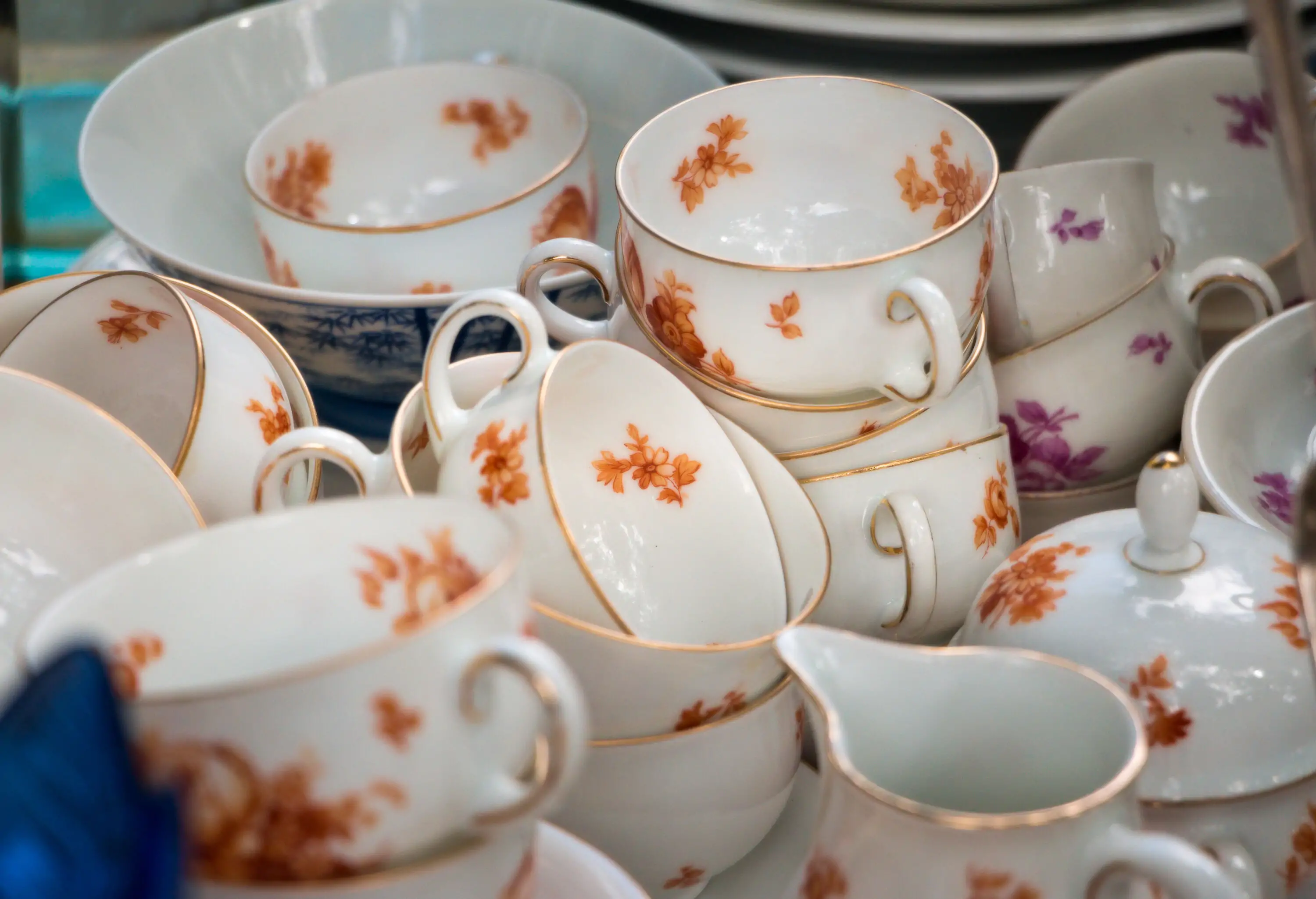 A bunch of antique tea cups with colourful floral designs.