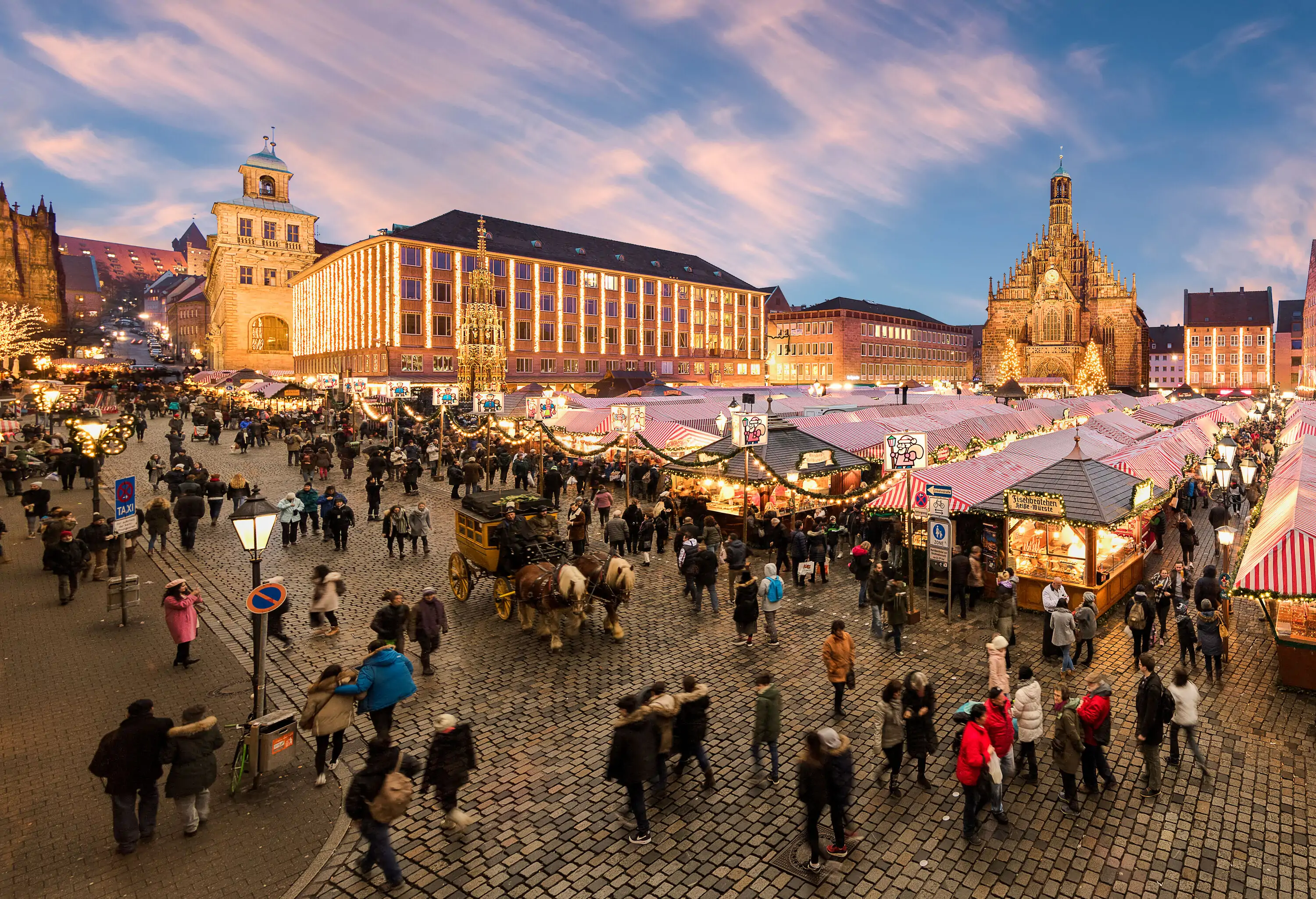 A large market square with rows of Christmas stores, a church in the Gothic style, and other old buildings.