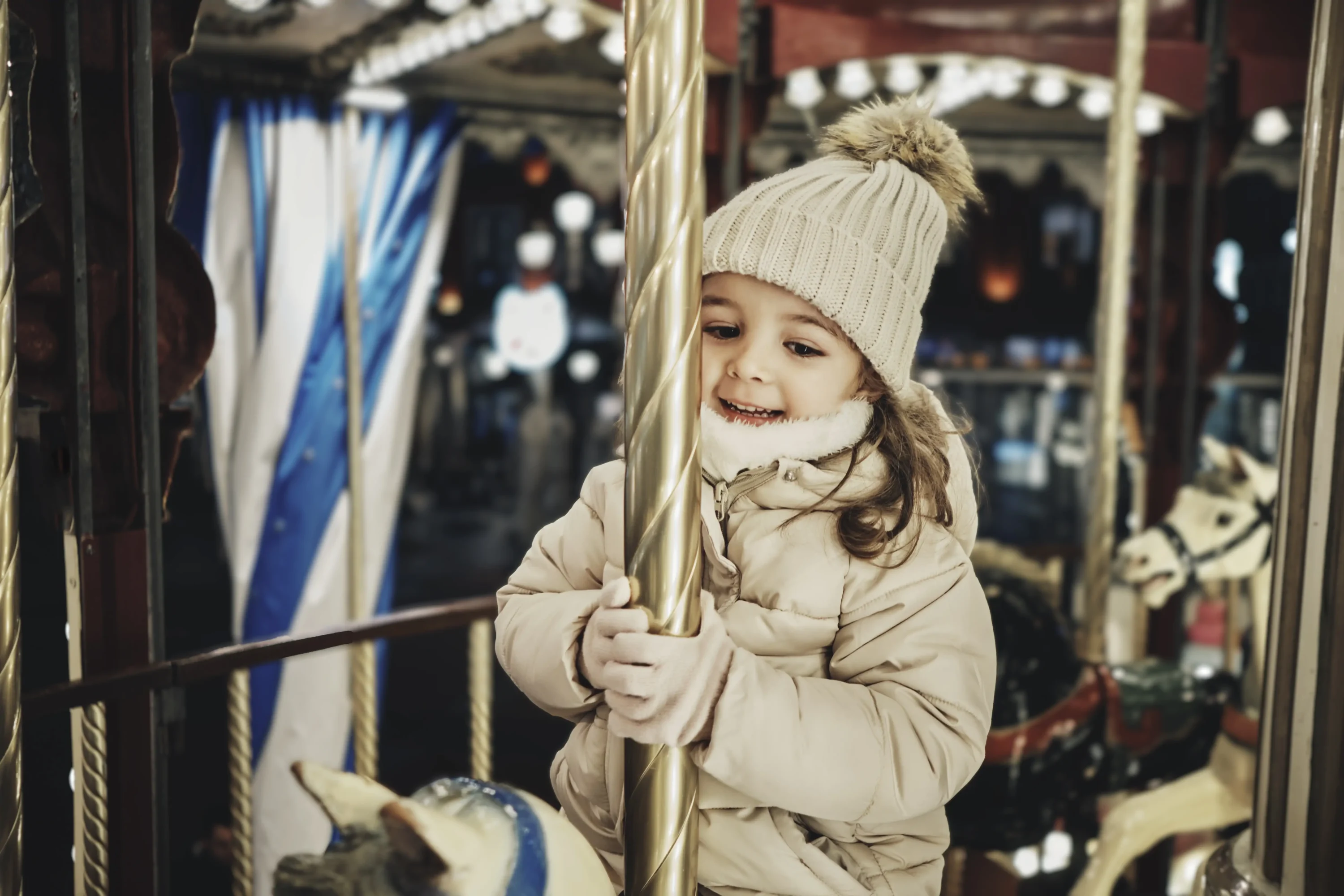 smiling girl enjoying carousel horse ride at Christmas market