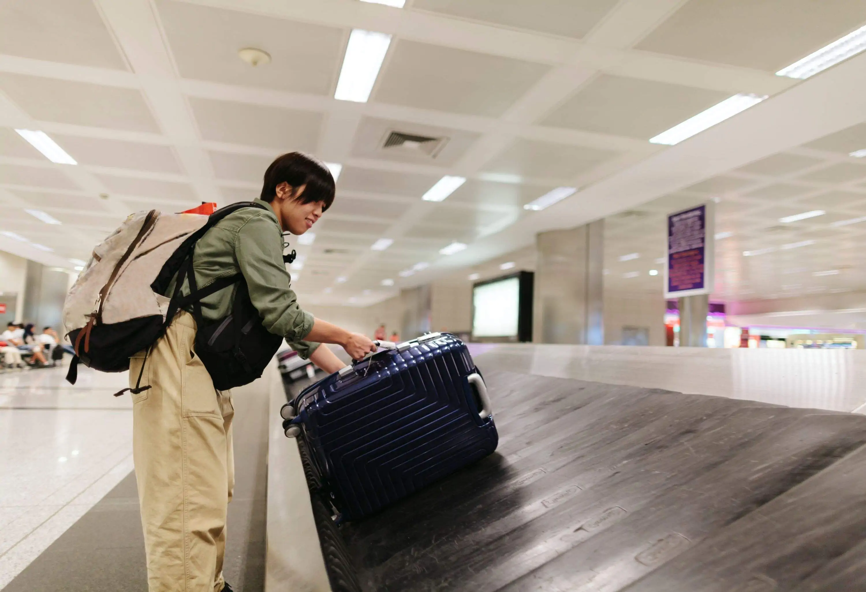 A Japanese young woman is picking up her luggage at airport baggage claim