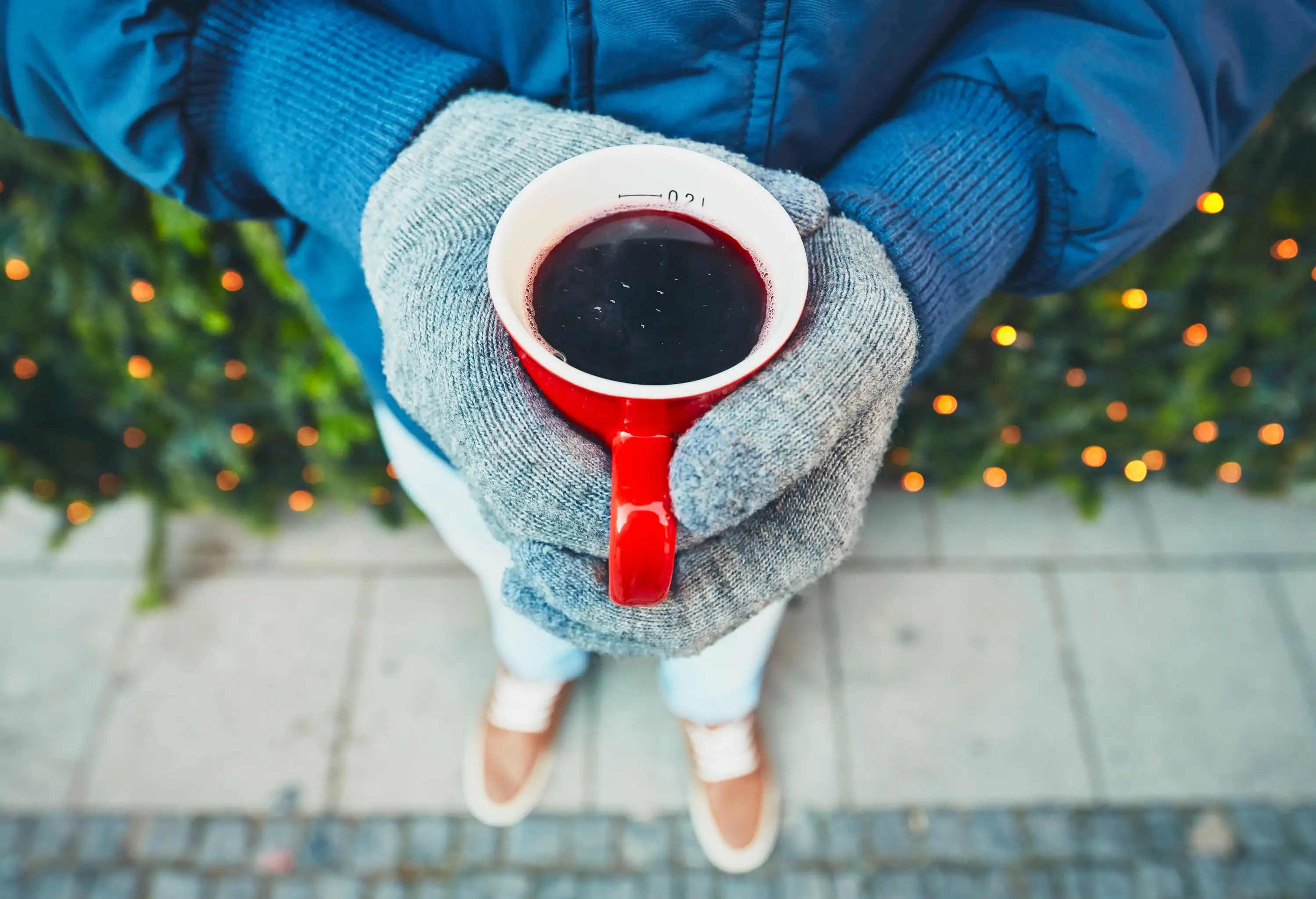 A man with a jacket and gloves holds a red beverage cup.