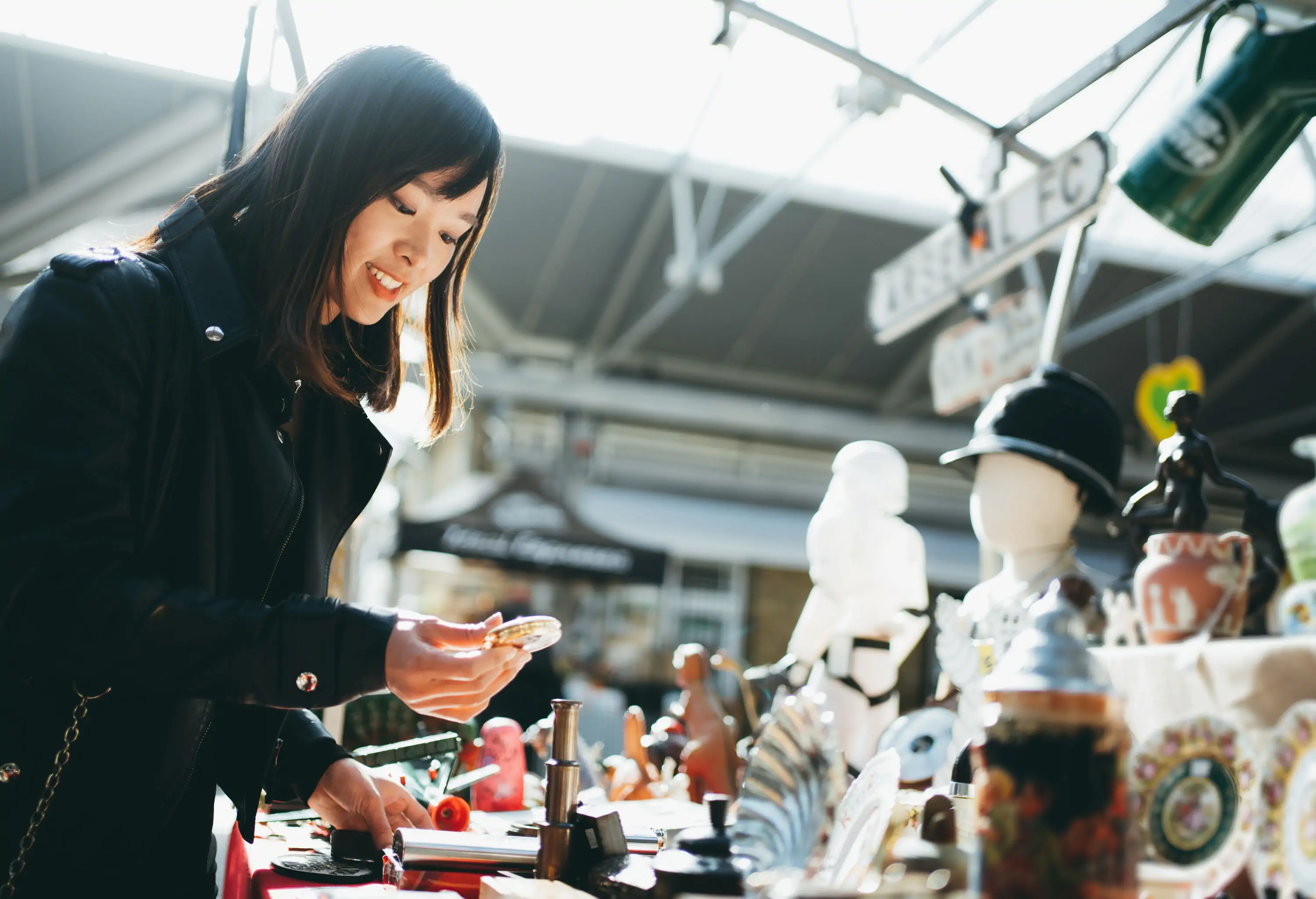 A young woman browsing through a display of items at a market.