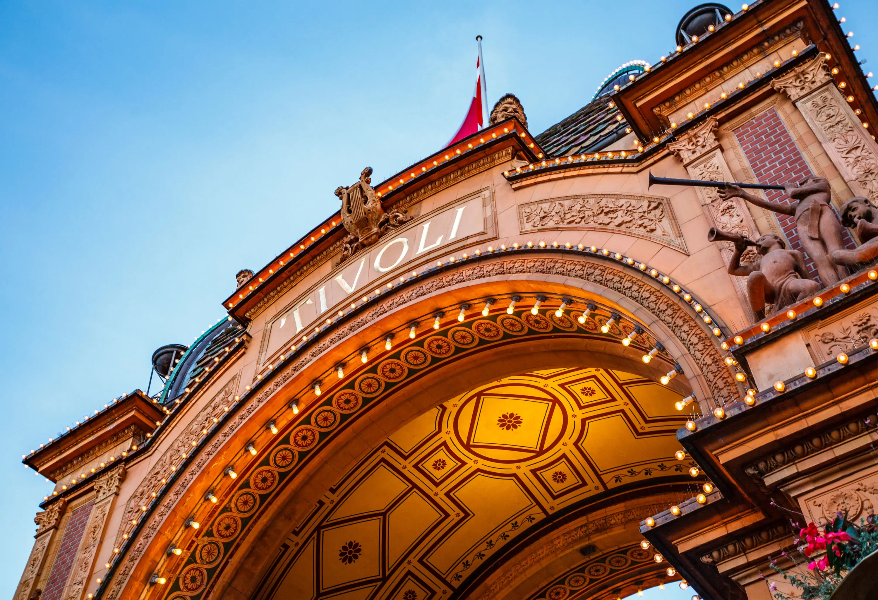 A gateway monument adorned with intricate sculptures and lighting with the words 