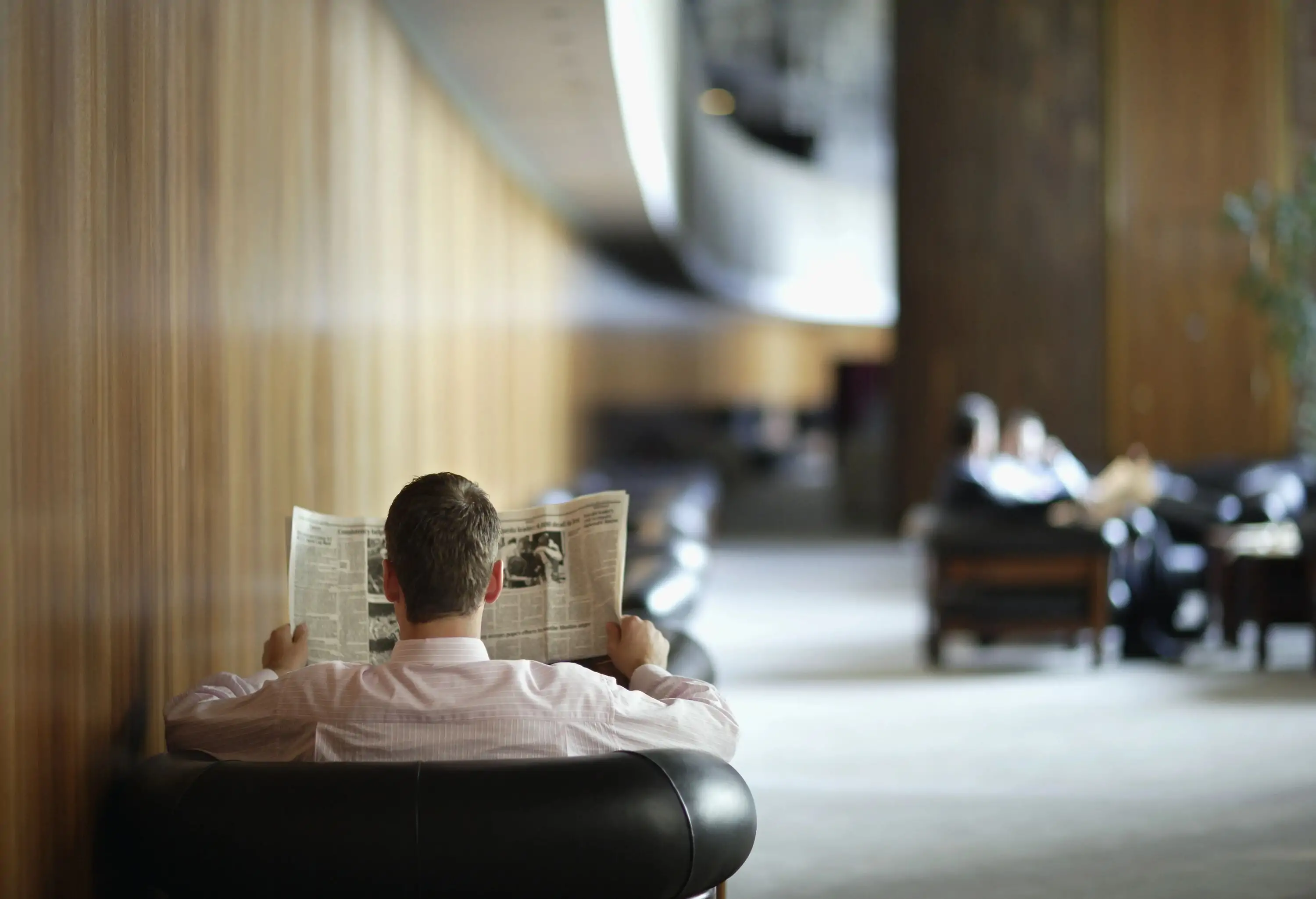 A man sitting in a hotel lobby holding a newspaper