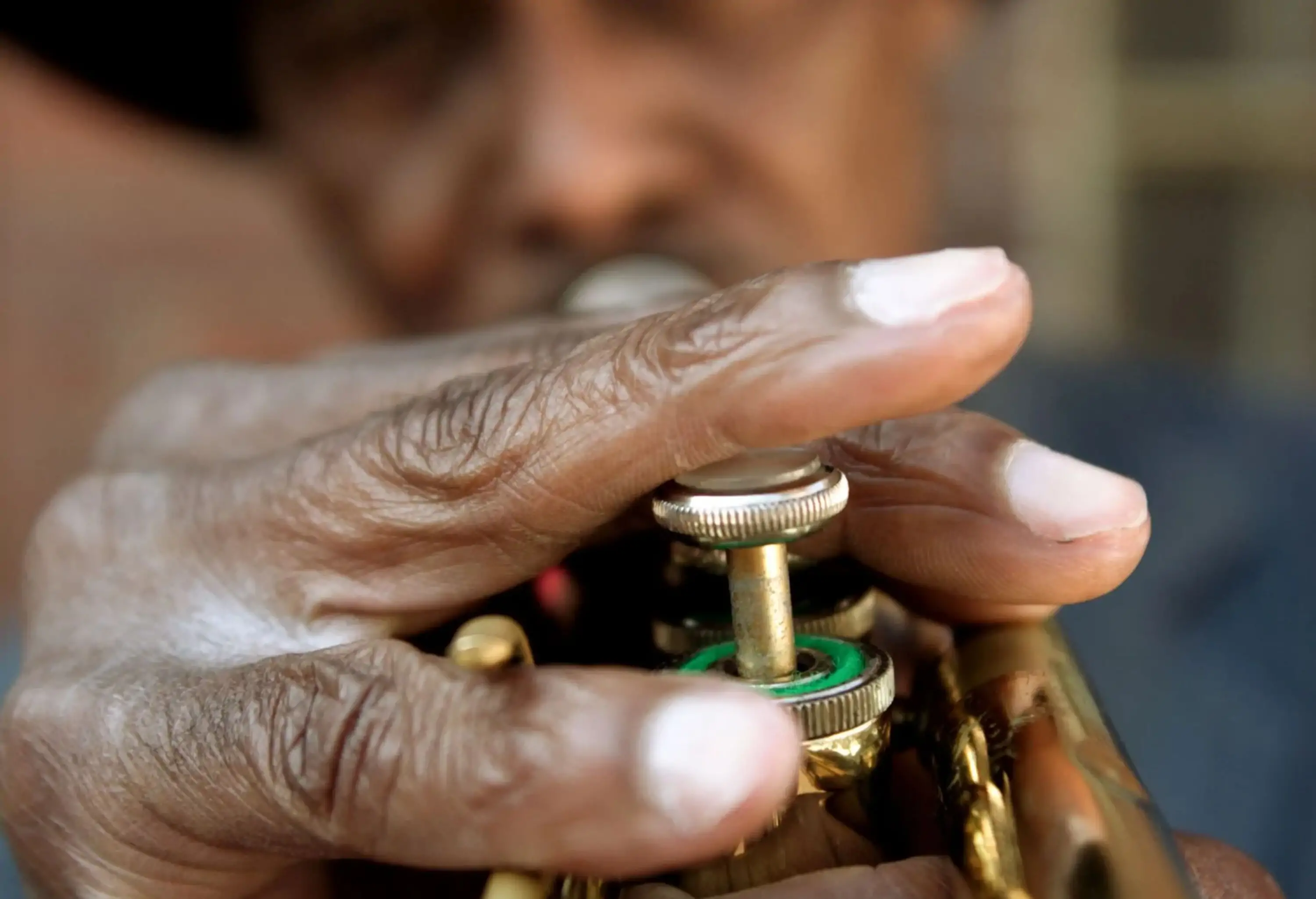 An elderly man with a hat playing a trumpet.