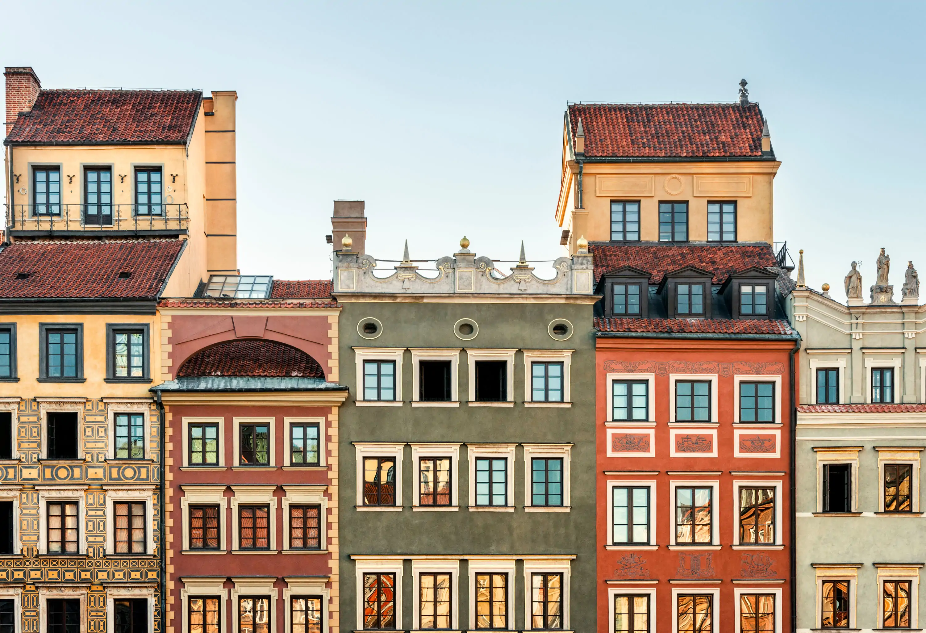 A row of colourful tall buildings extends to the cloudless sky.