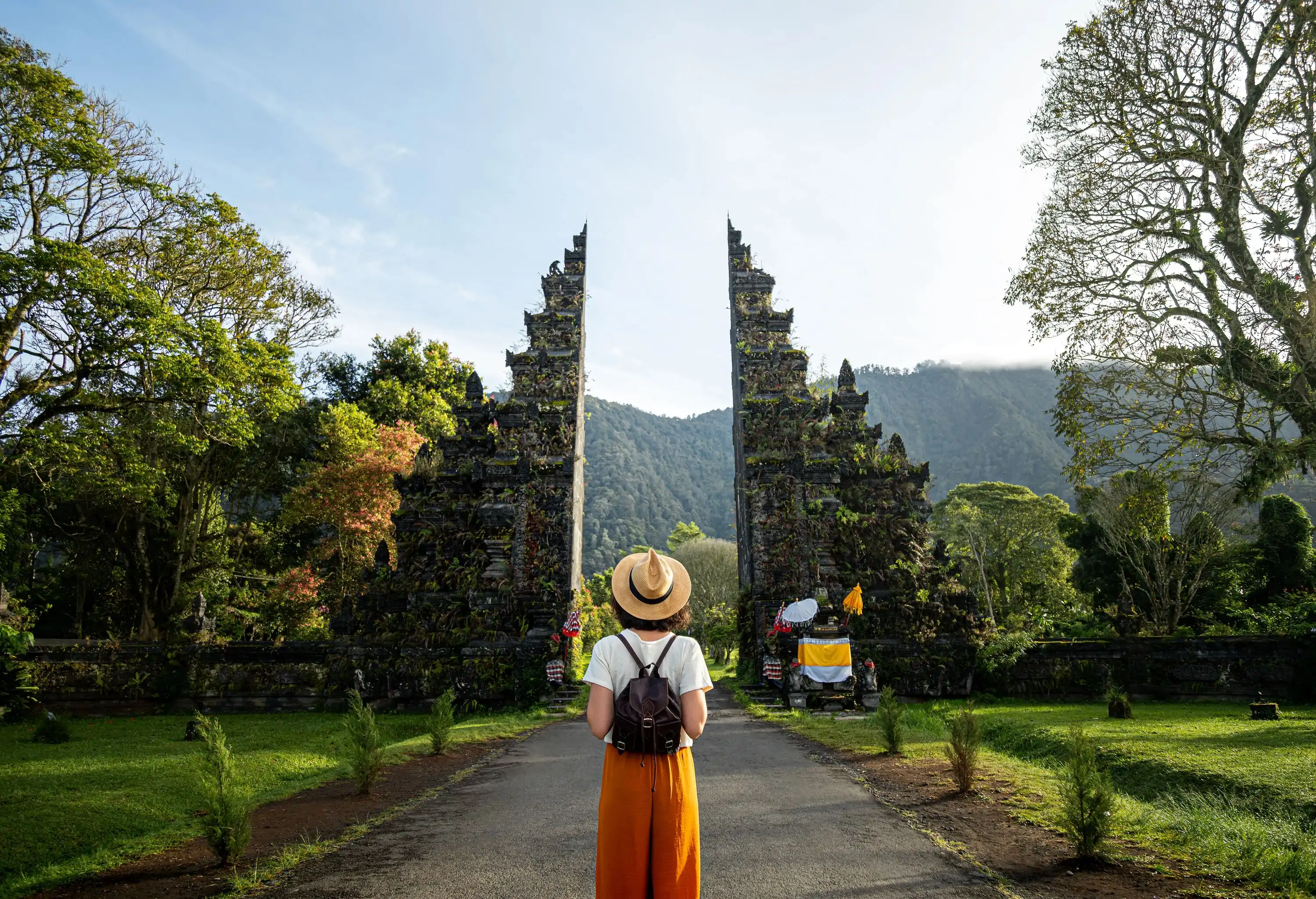 Woman tourist traveler with backpack enjoying walk through Balinese Hindu temple during vacation in Asia. Woman contemplating monument during holidays.