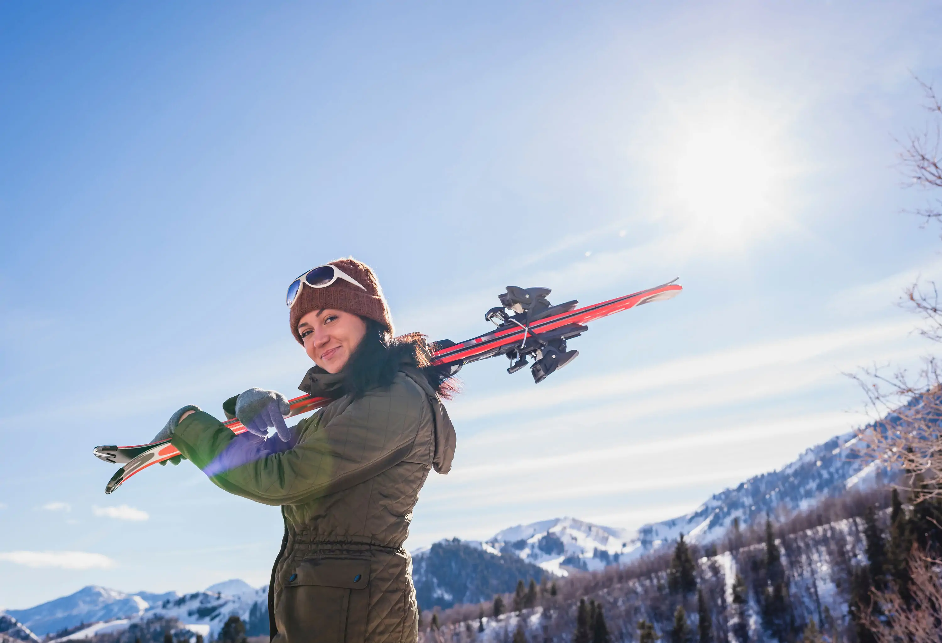 A woman with her skis slung over her shoulder.