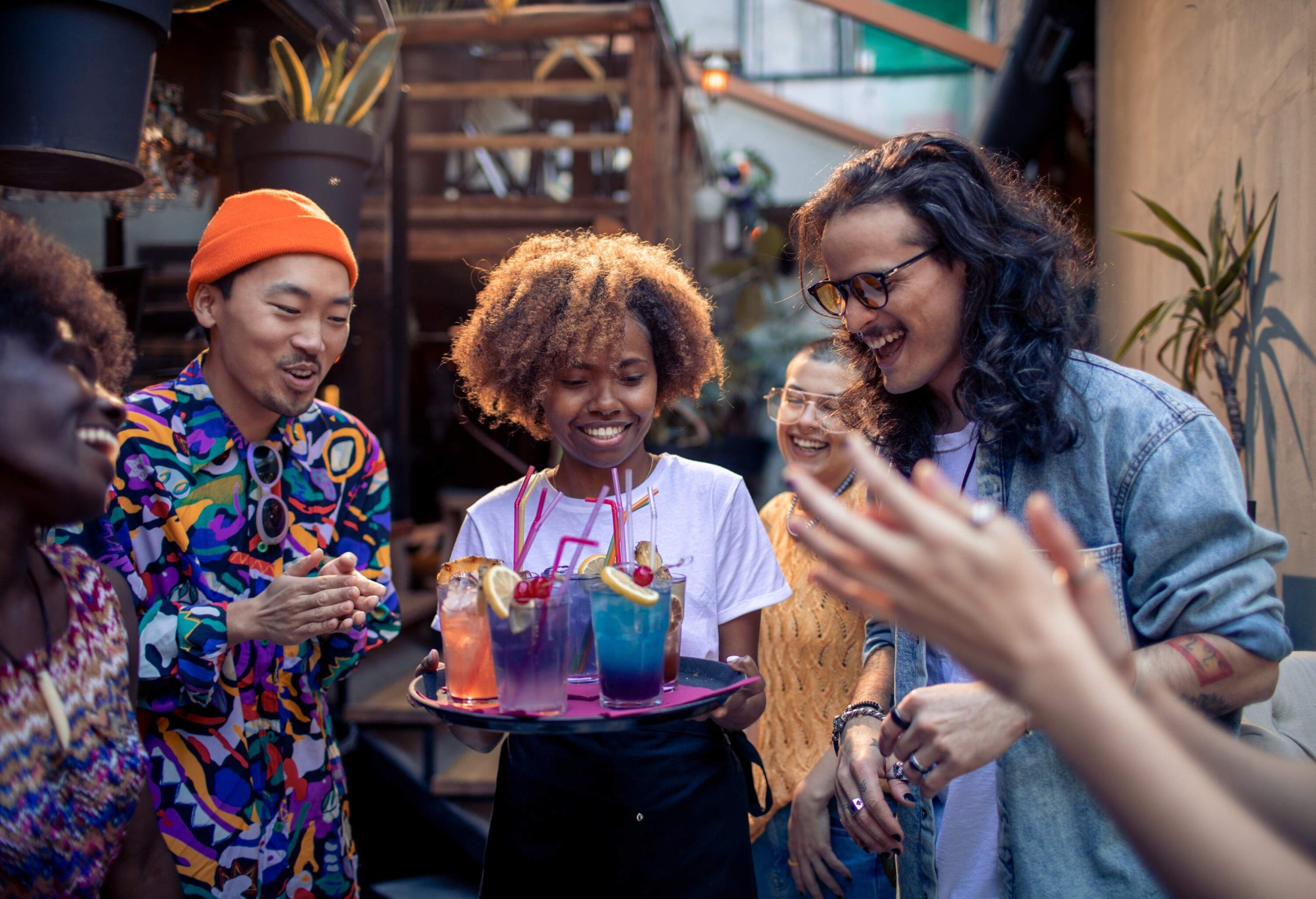 A female bartender serves various drinks to the customers in the bar.