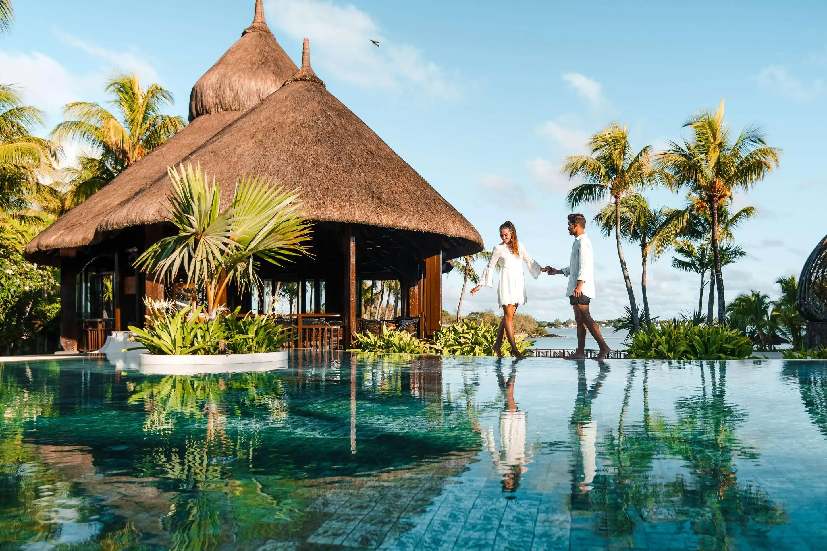 Couple holding hands by infinity pool in a luxury beach hotel on a tropical island