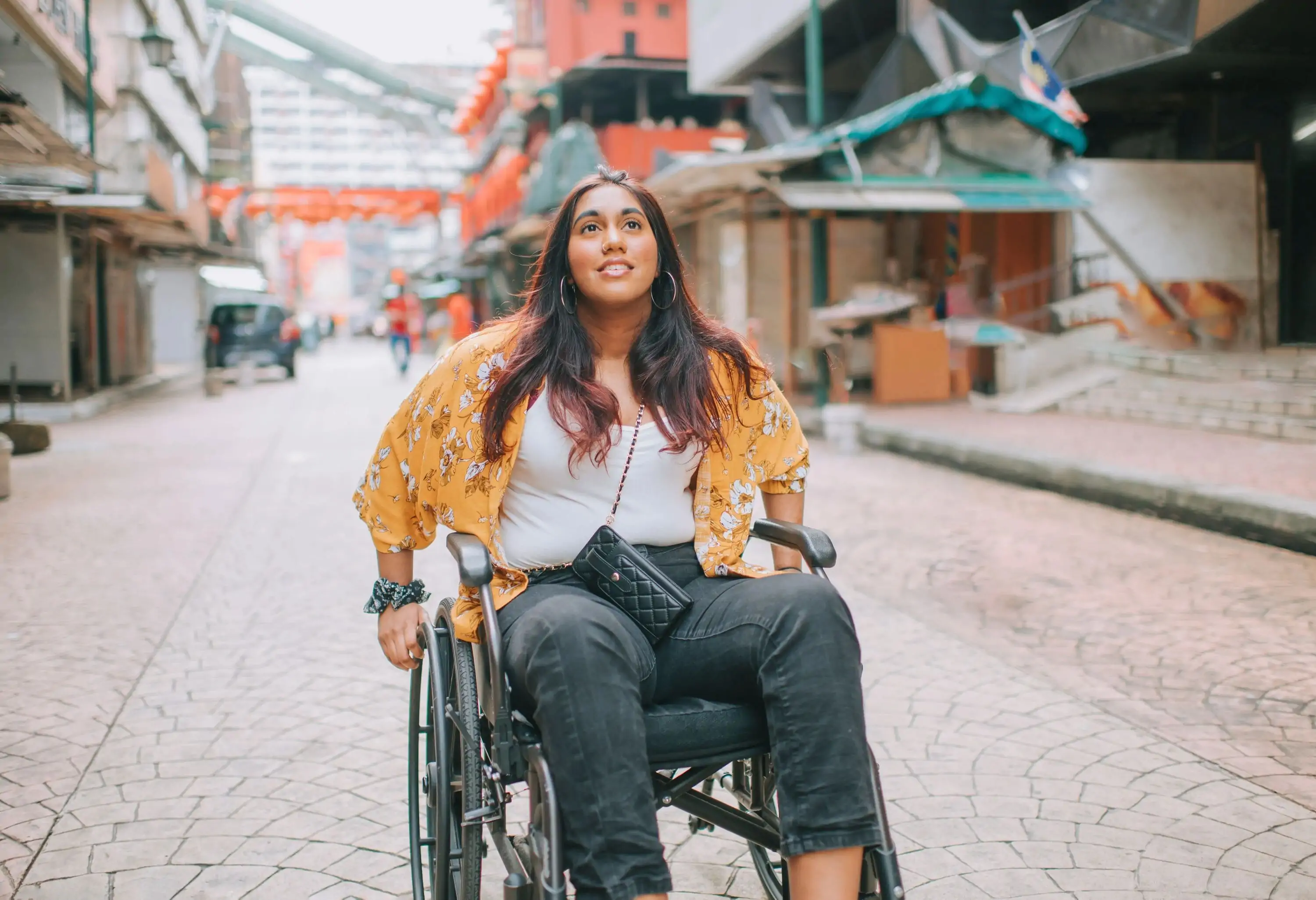 A woman in a wheelchair parked in the middle of a city centre street.