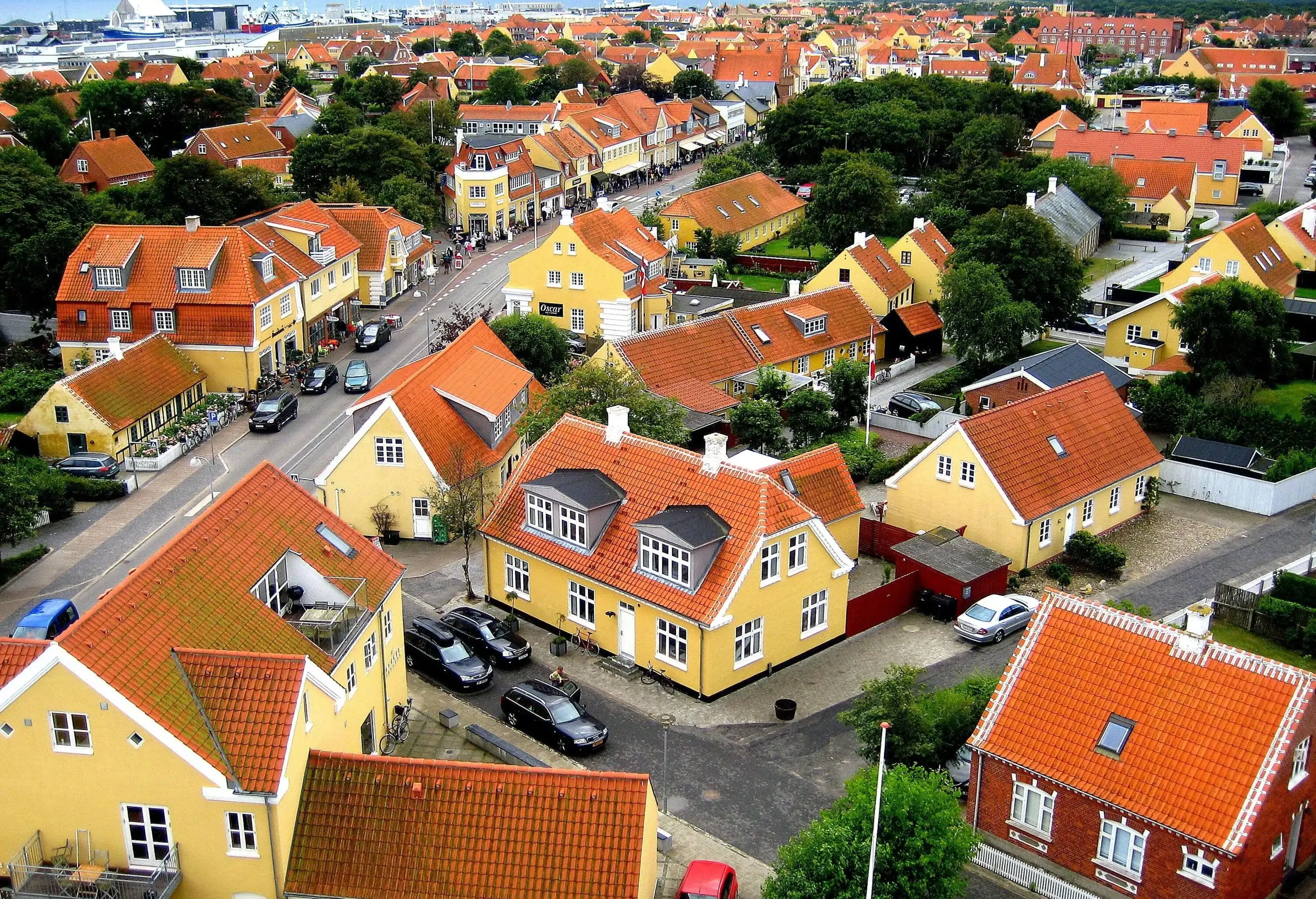 A road across a residential area of yellow homes with red tiled roofs.