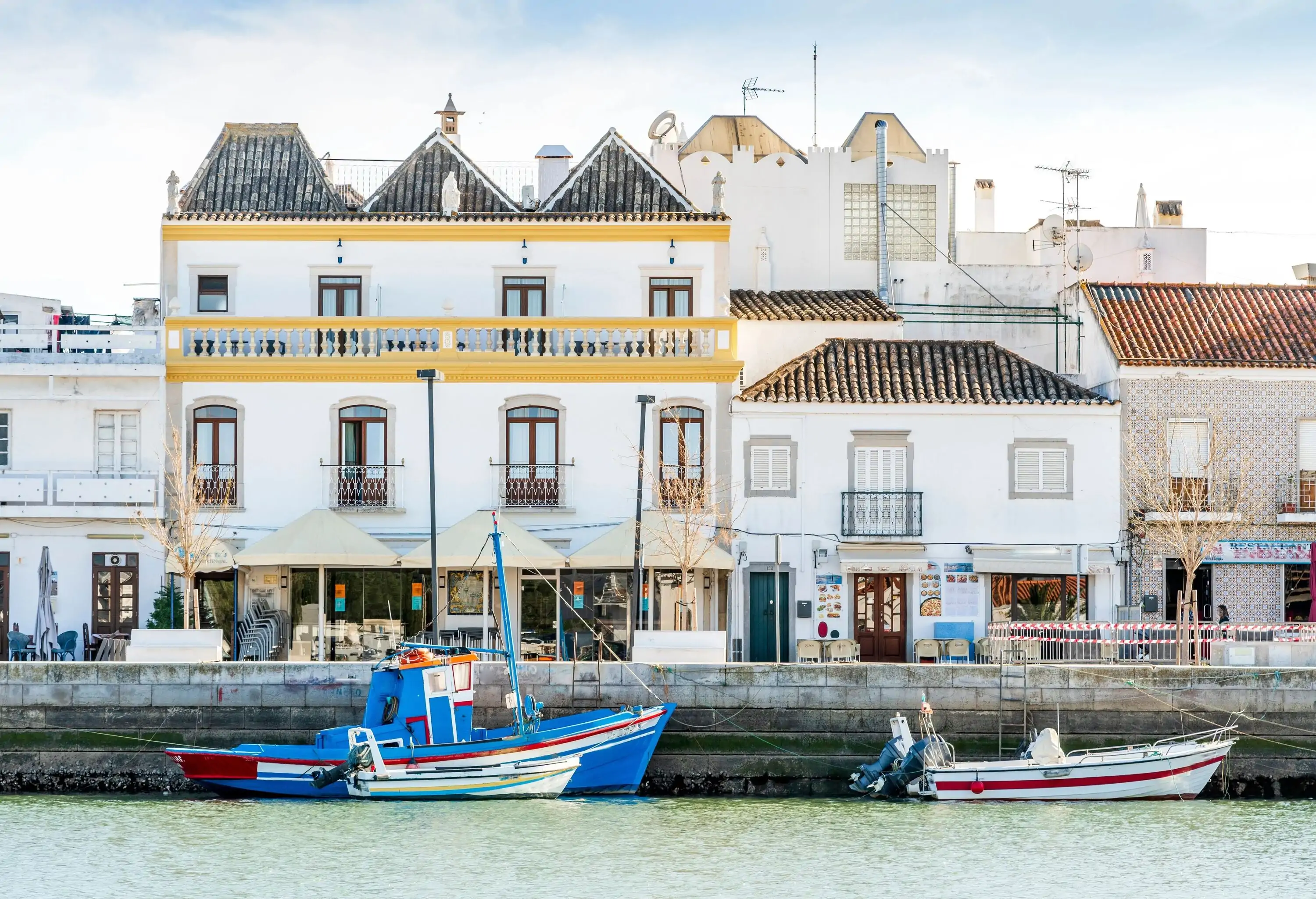 Two fishing boats along the harbour wall in front of old town buildings.